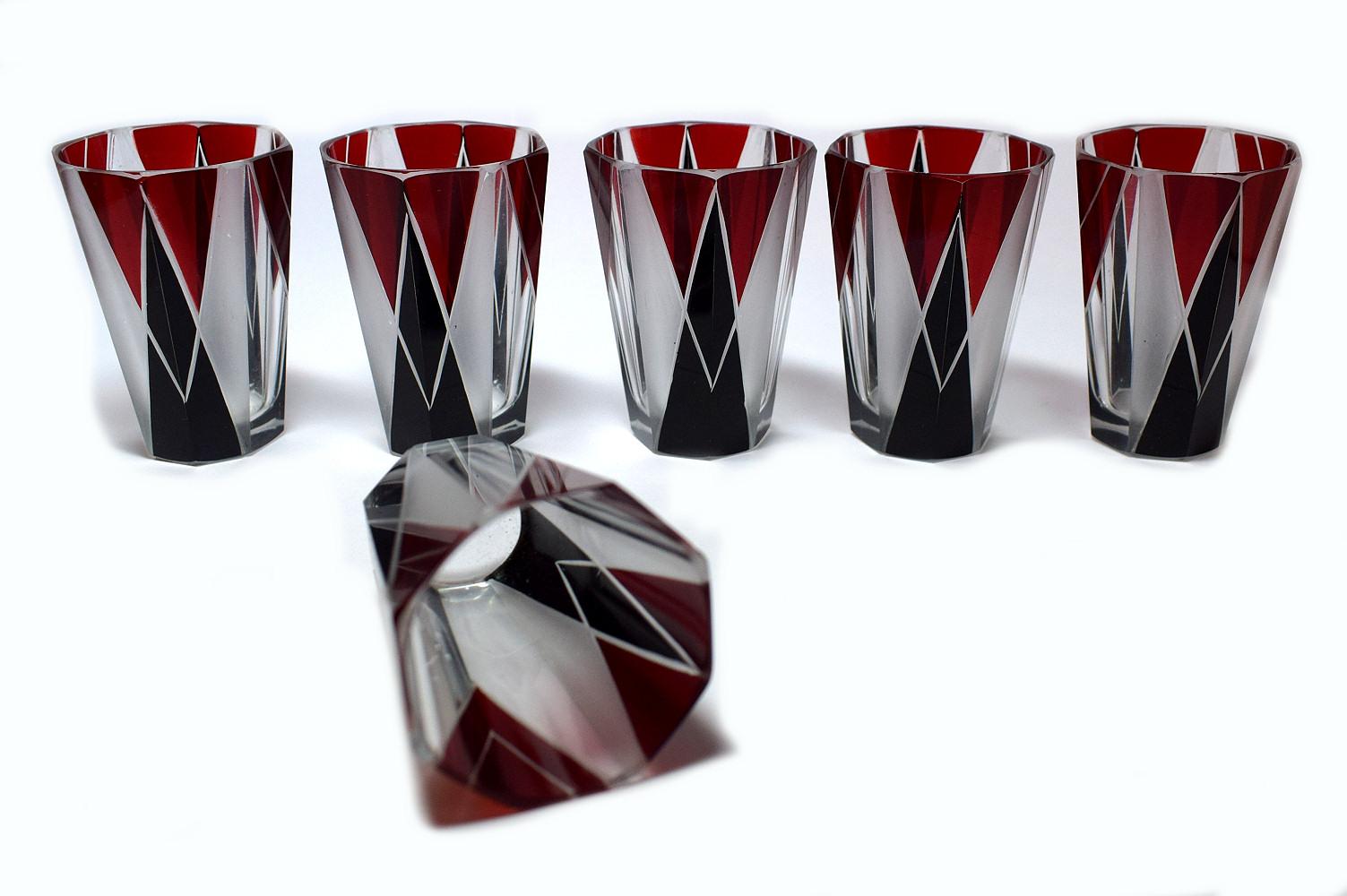 Ensemble de carafes Art Déco tchèque des années 1930 en verre transparent avec décor en émail noir et rouge profond. La carafe est accompagnée de six verres assortis, l'ensemble étant fortement émaillé de décorations géométriques. Le couvercle est