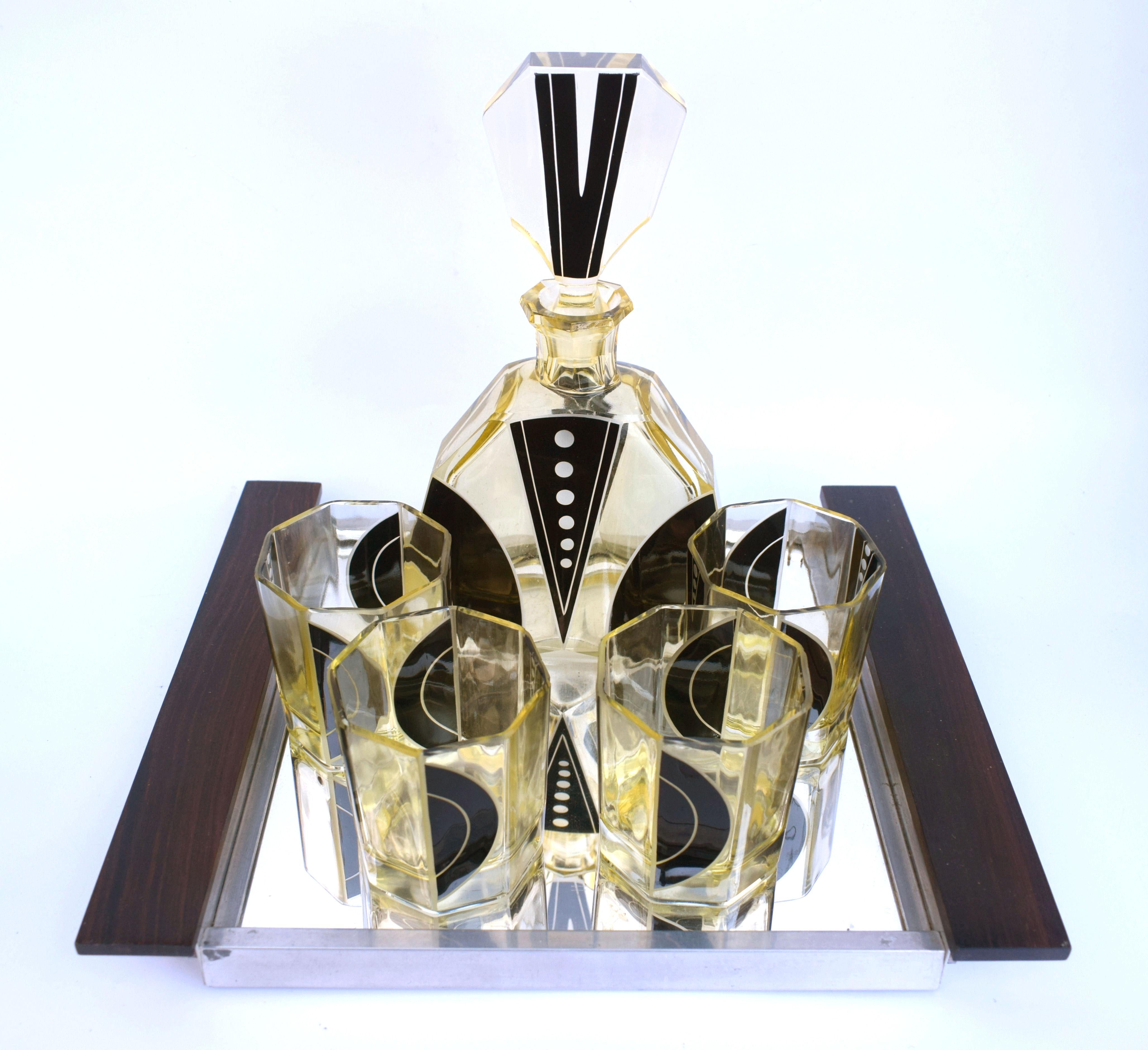 Very stylish and appealing Art Deco decanter set which comes with six matching glasses, and decanter, the whole being heavily enamelled with geometric decoration. The colour is a lemon yellow with black enamelling and etched accents and the