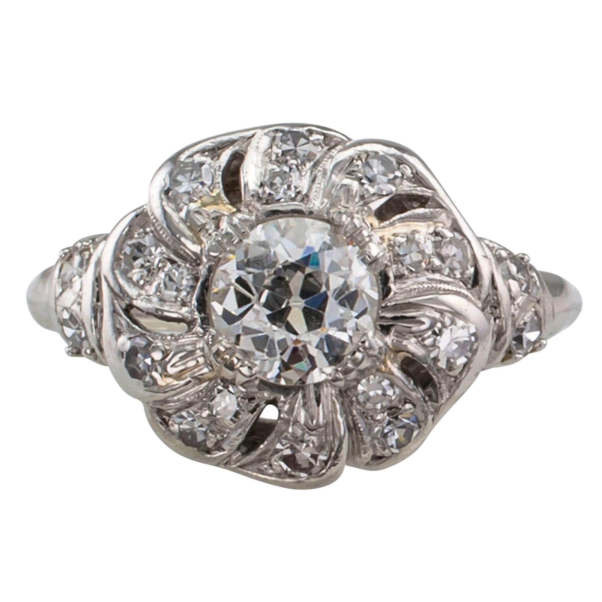 Late Art Deco 1930s diamond and platinum engagement ring. Designed as a flower centering an old European-cut diamond weighing approximately 0.60 carat, approximately I - J color and SI clarity, surrounded by petals to the shoulders set with smaller
