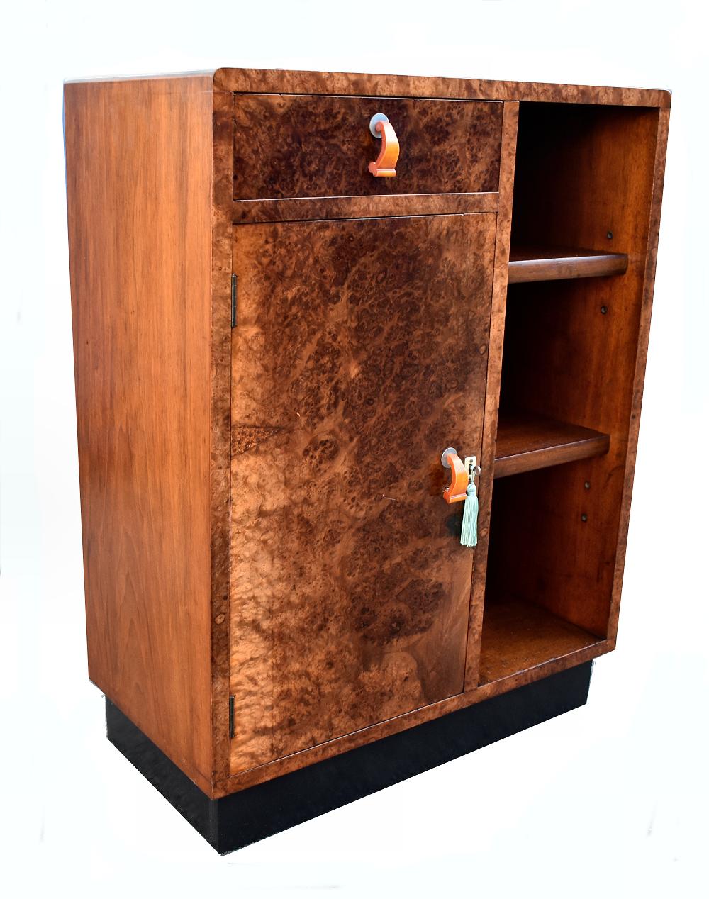 Stylish 1930s Art Deco cupboard with open book shelving. Fabulous walnut veneers that are heavily figured making this piece look very exotic. Generous storage provided by a single drawer and cupboard with an internal shelf and an open adjustable