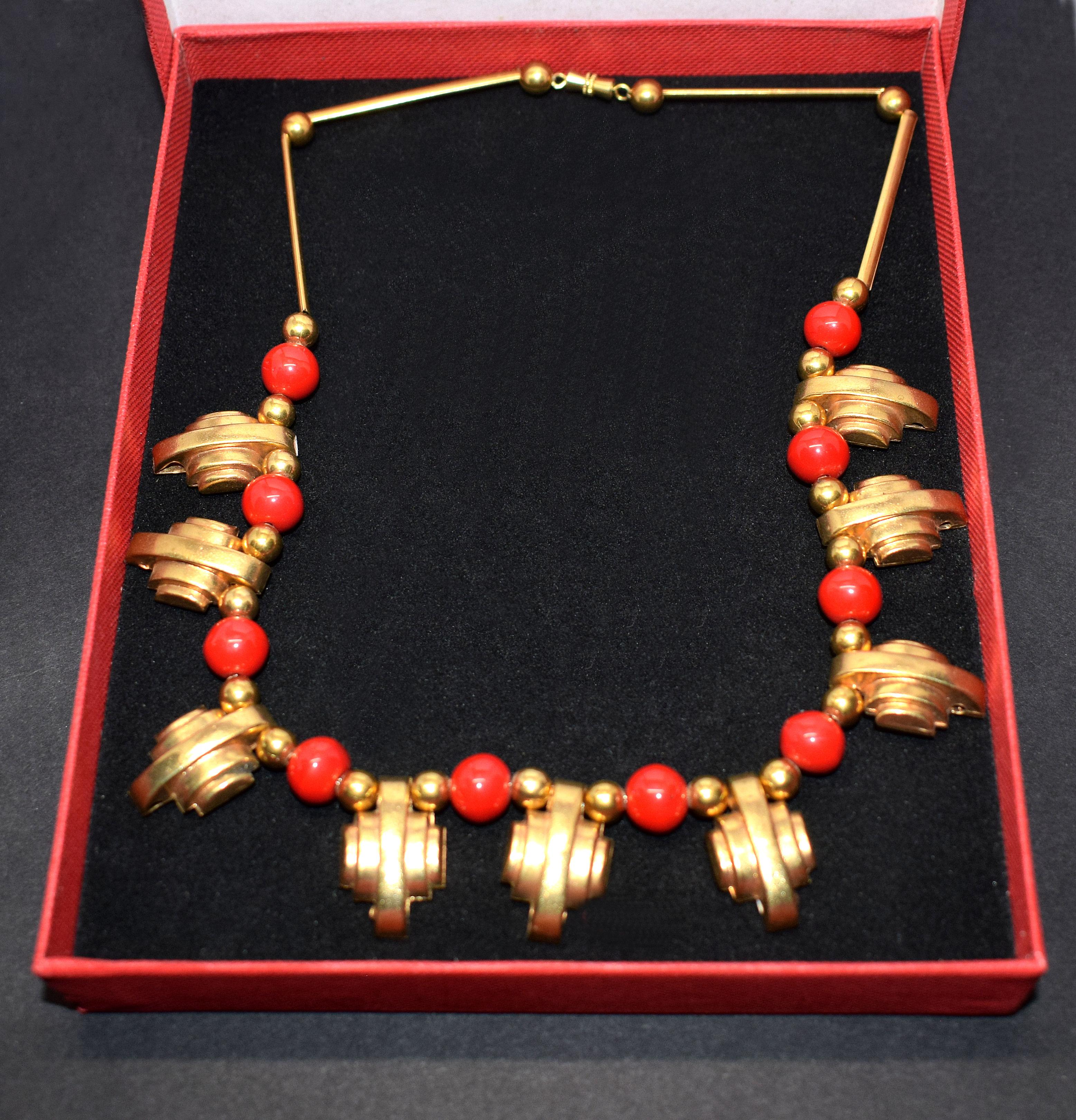 Timeless Art Deco ladies necklace dating to the 1930's. Gold tone metal makes up the body of the necklace with streamline odeon shaped pieces and alternating berry red galalith balls. So easily integrated with today's modern fashion savvy lady which