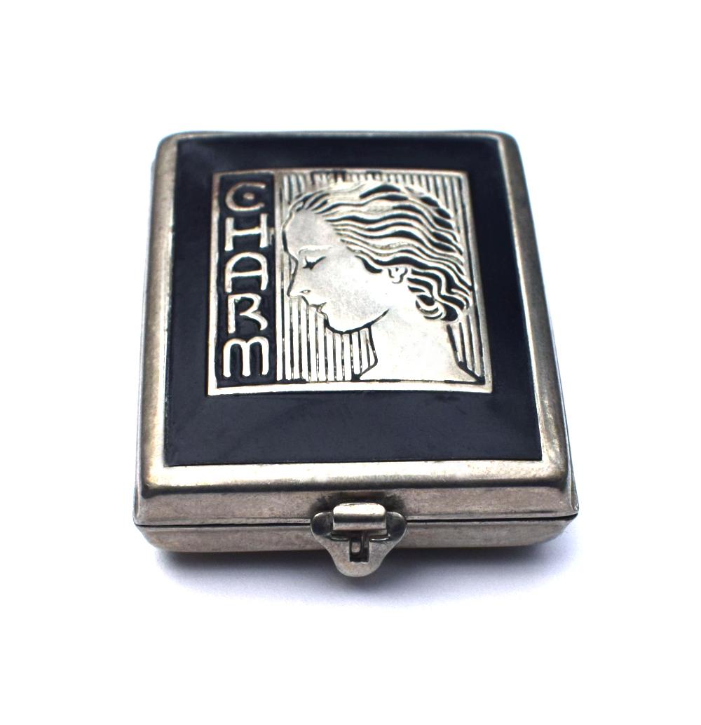 A rare little gem is this delightful 1930's Art Deco ladies powder compact. Classic chrome and black enamel which depicts the profile of a stylized Art Deco lady and the embossed letters 'Charm'. Comes with original rouge and applicator pad inside,