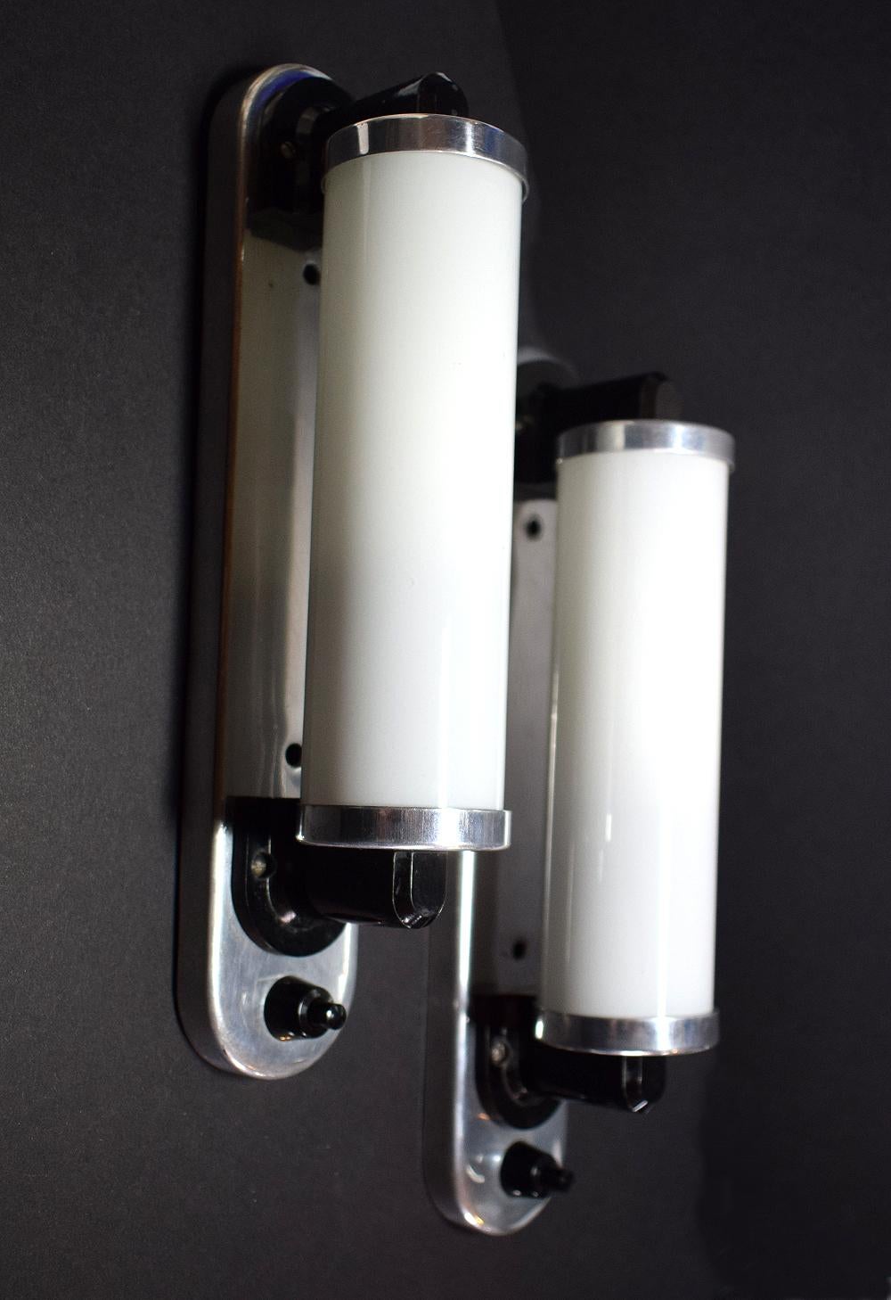 For your consideration is this small Modernist Art Deco matching pair of wall light sconces with a black bakelite switch. Opaline tubular glass in highly polished aluminium frames. Ideal for bathrooms, hallways or any where that needs framing with