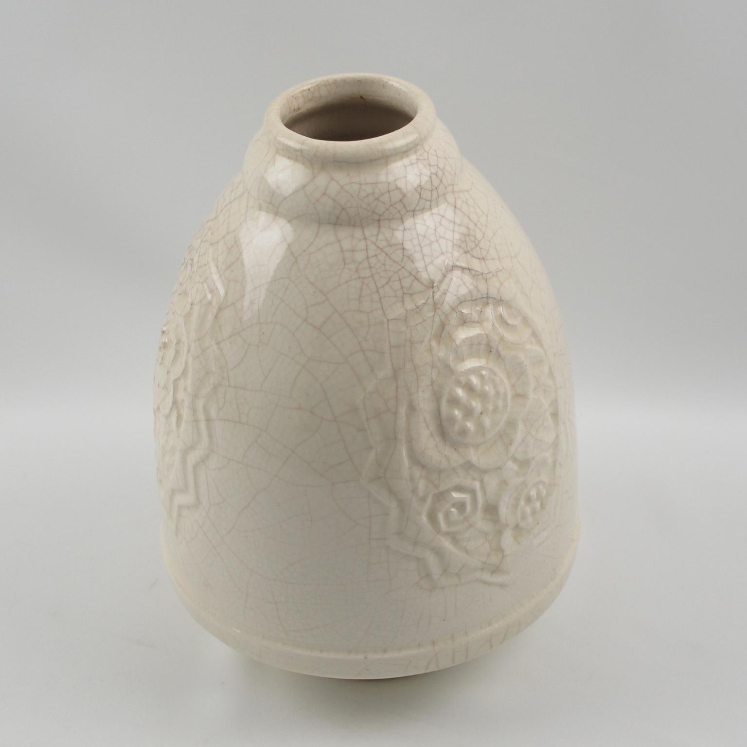 Elegant Art Deco vase by Saint Clement, France. French ceramic vase with off-white crackle glaze finish. Features a large squash puffy shape with small collar opening and detailed carved stylized floral design all around (three design around vase).