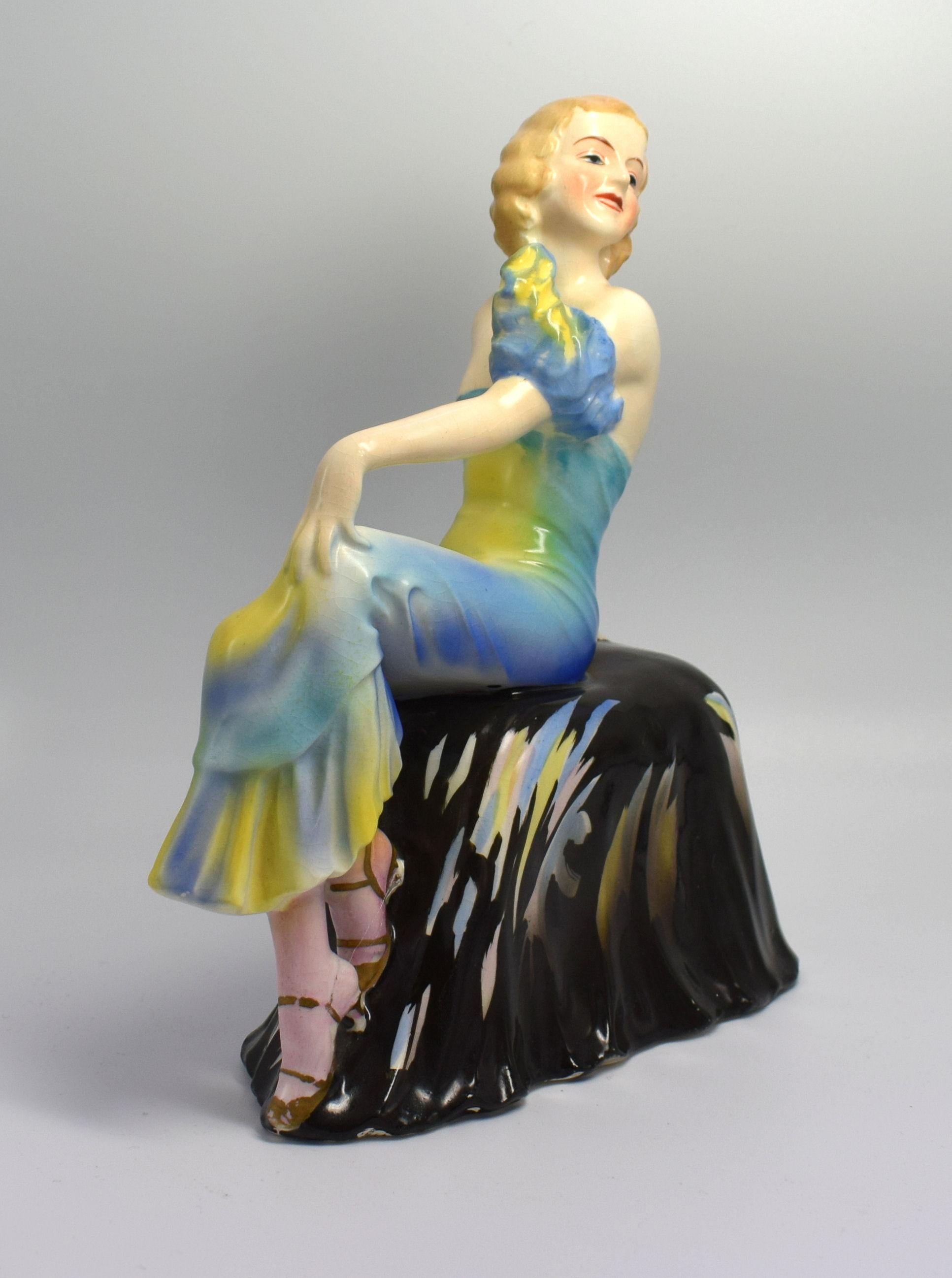 A beautiful, elegant, stylish, Art Deco lady figurine seated on a draped seat. She is in excellent condition with no cracks, chips or restoration. There is some crazing to the glaze, which can be seen on very close inspection. She's been very
