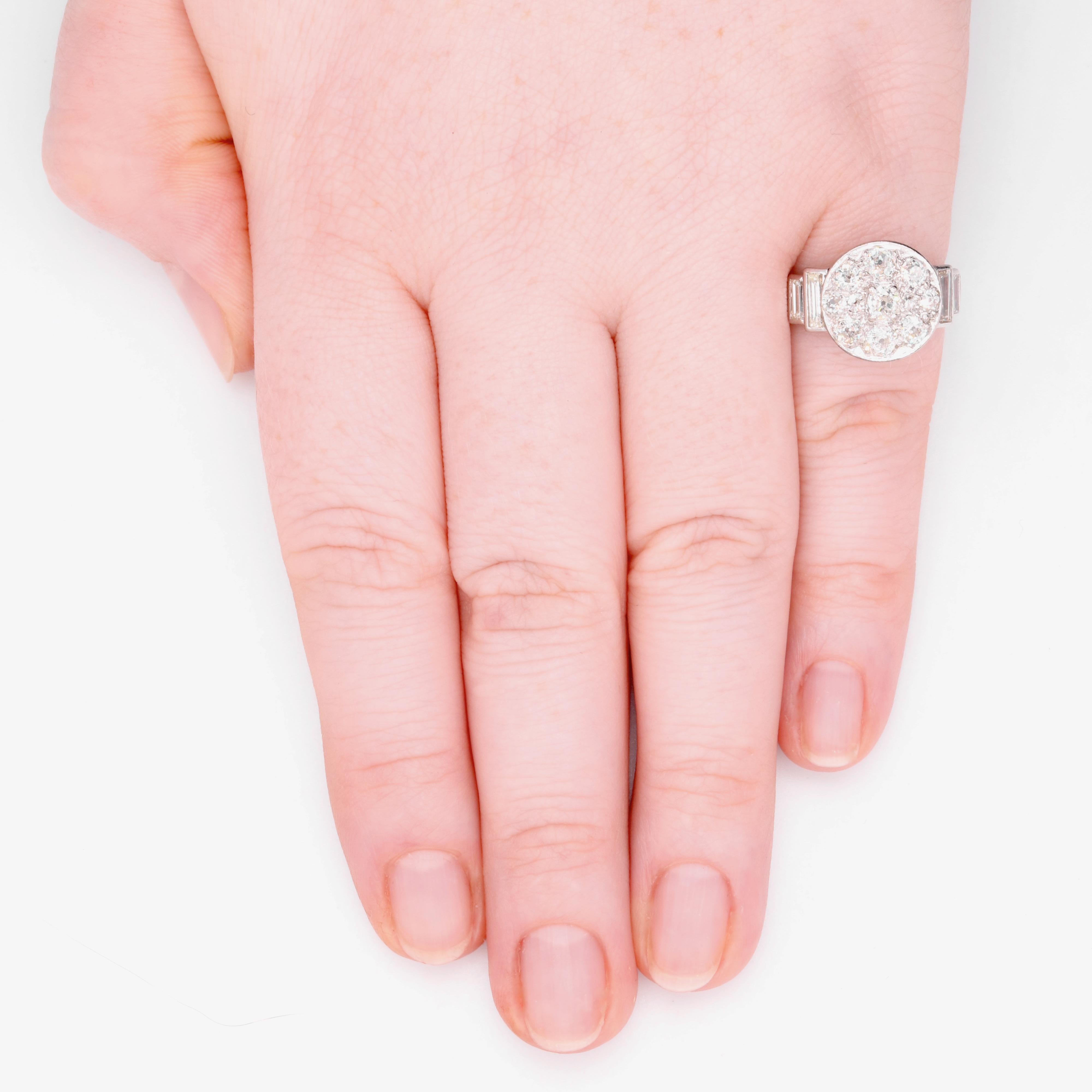 Ein Art-Deco-Diamant- und Platinring, bestehend aus elf Diamanten im Altminenschliff und sechs Diamanten im Baguetteschliff, gefasst in Platin und 18 Karat Weißgold, an einem Platinband.  

Dieser auffällige Art-Déco-Ring ist in der Mitte mit einem