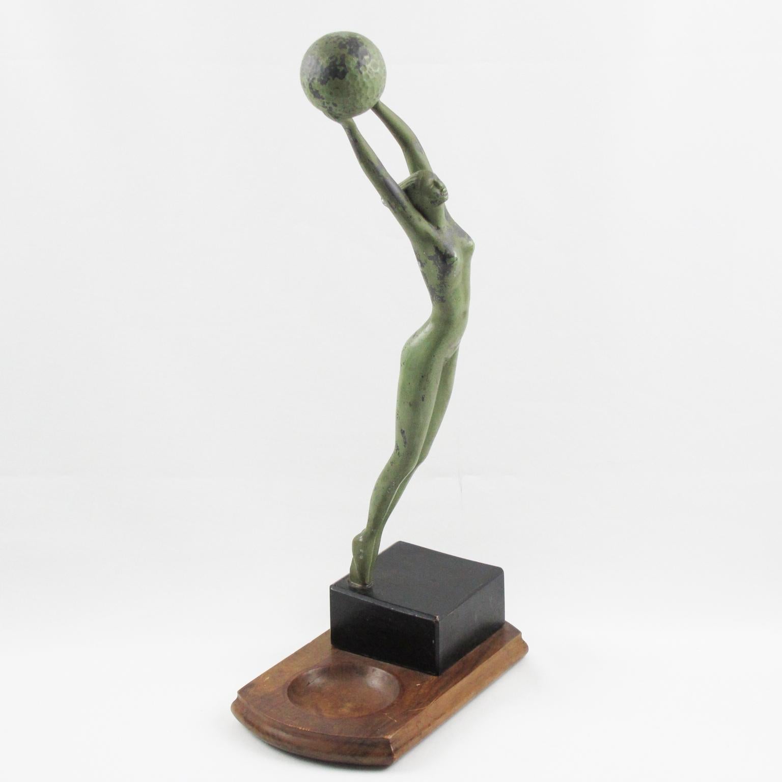 Elegant metal sculpture, statuette signed on base. Finely carved bare slim naked woman in a typical Art Deco period design, holding a golf ball. The figurine is made of white metal with an original green patina. Desk tidy base in natural walnut wood