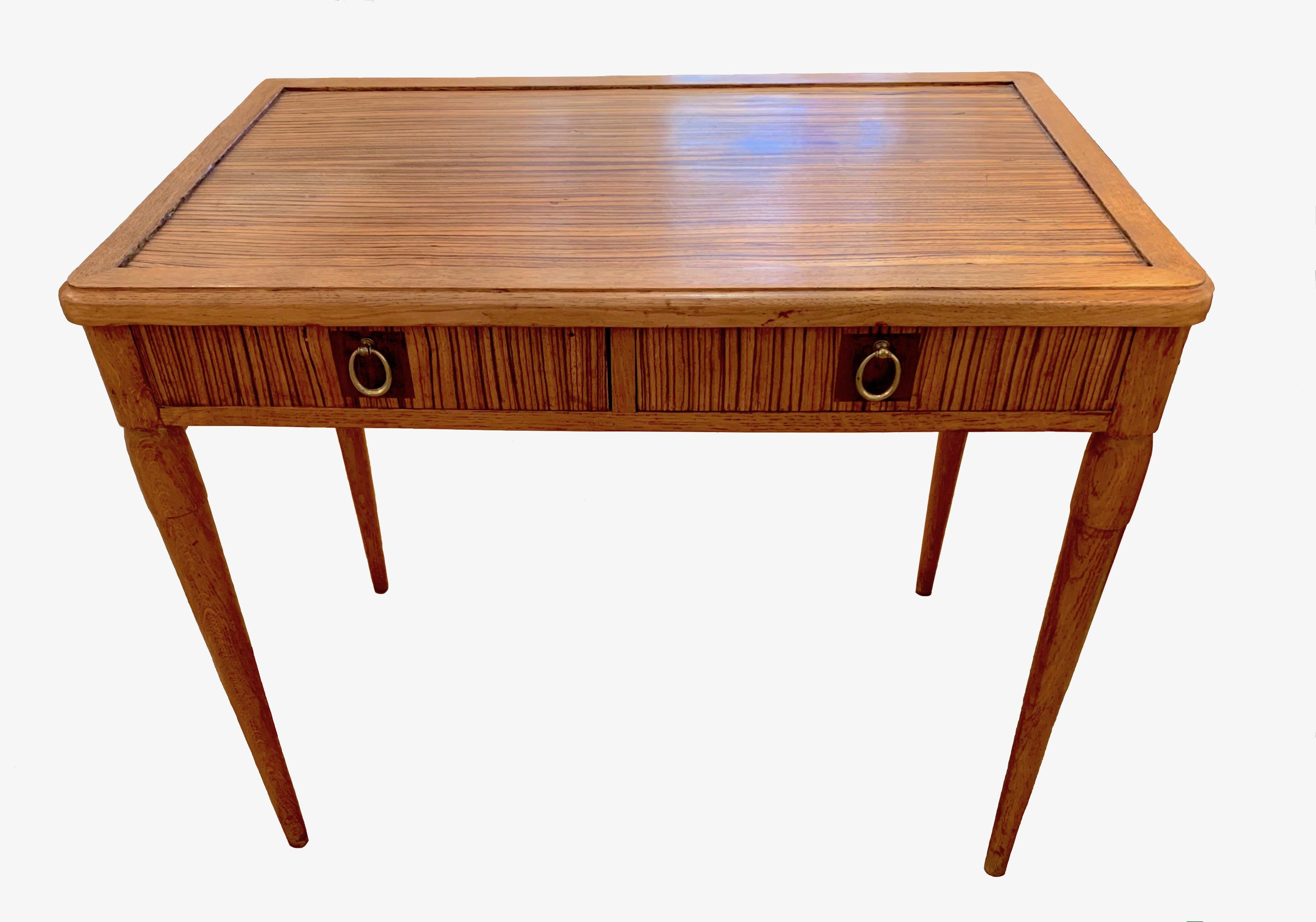 Cette élégante table à écrire a été fabriquée à la main en France dans les années 1940. La table est composée de trois types de bois différents et d'anneaux en laiton forgé. Le plateau de la table et les deux tiroirs sont fabriqués dans le même