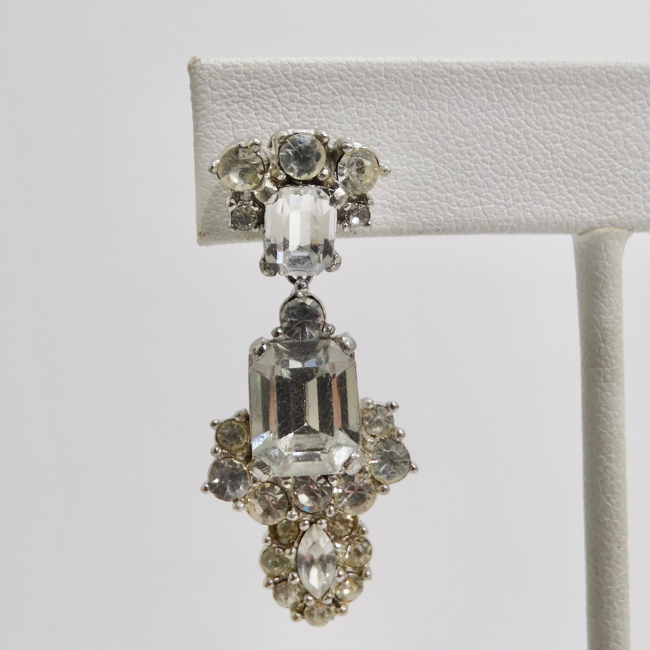 Step back in time and embrace the timeless elegance of our Art Deco 1940s Rhinestone Earrings. These exquisite dangle-style earrings boast a dazzling array of clear rhinestones, meticulously arranged to capture the essence of vintage glamour.