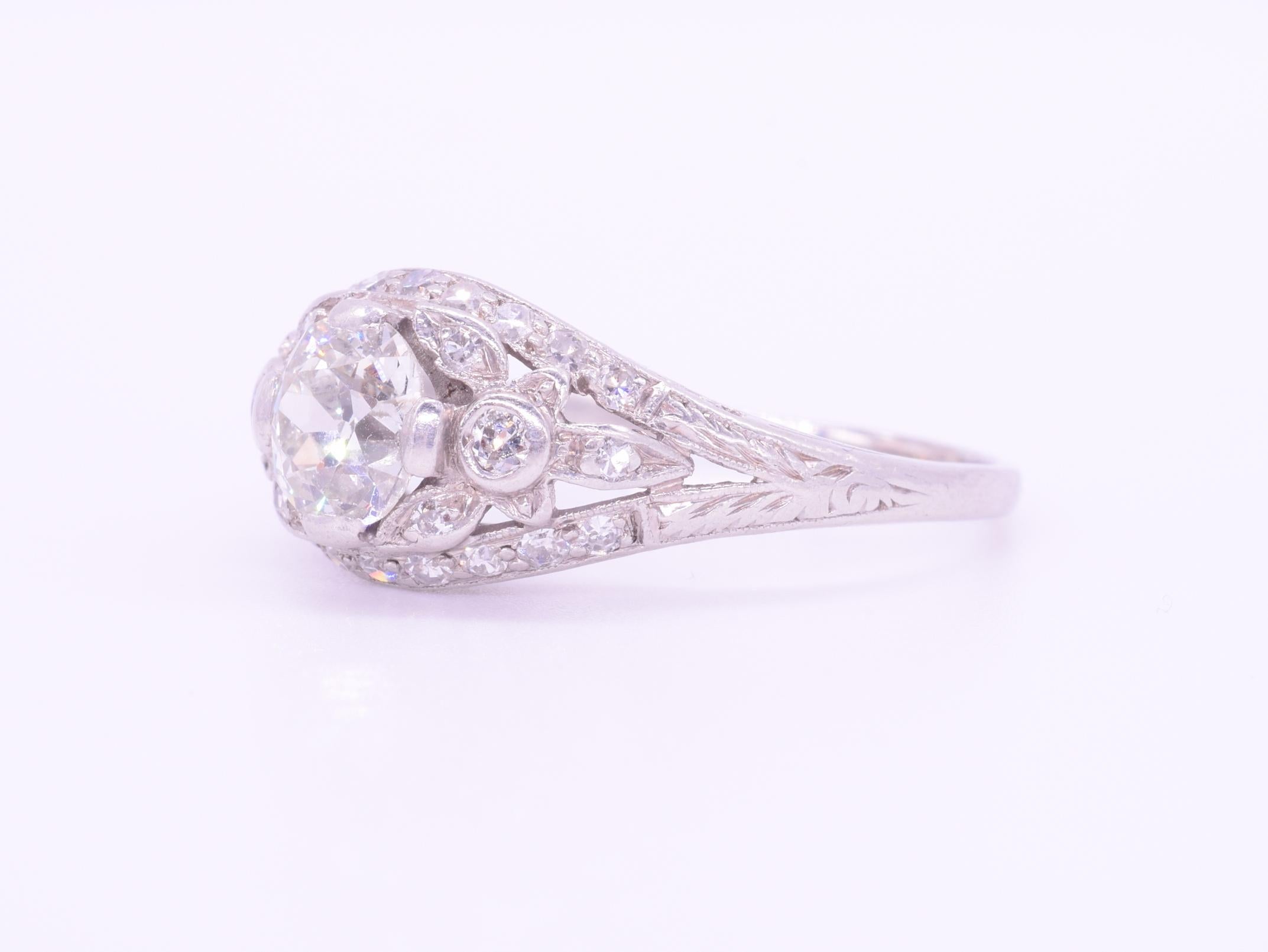 An old European cut diamond weighing approximately 1ct, of approximately  I-J color and SI clarity, is accented with a floral motif set with single cut diamonds totaling approximately  0.35ct mounted in platinum. Current ring size 8.75.