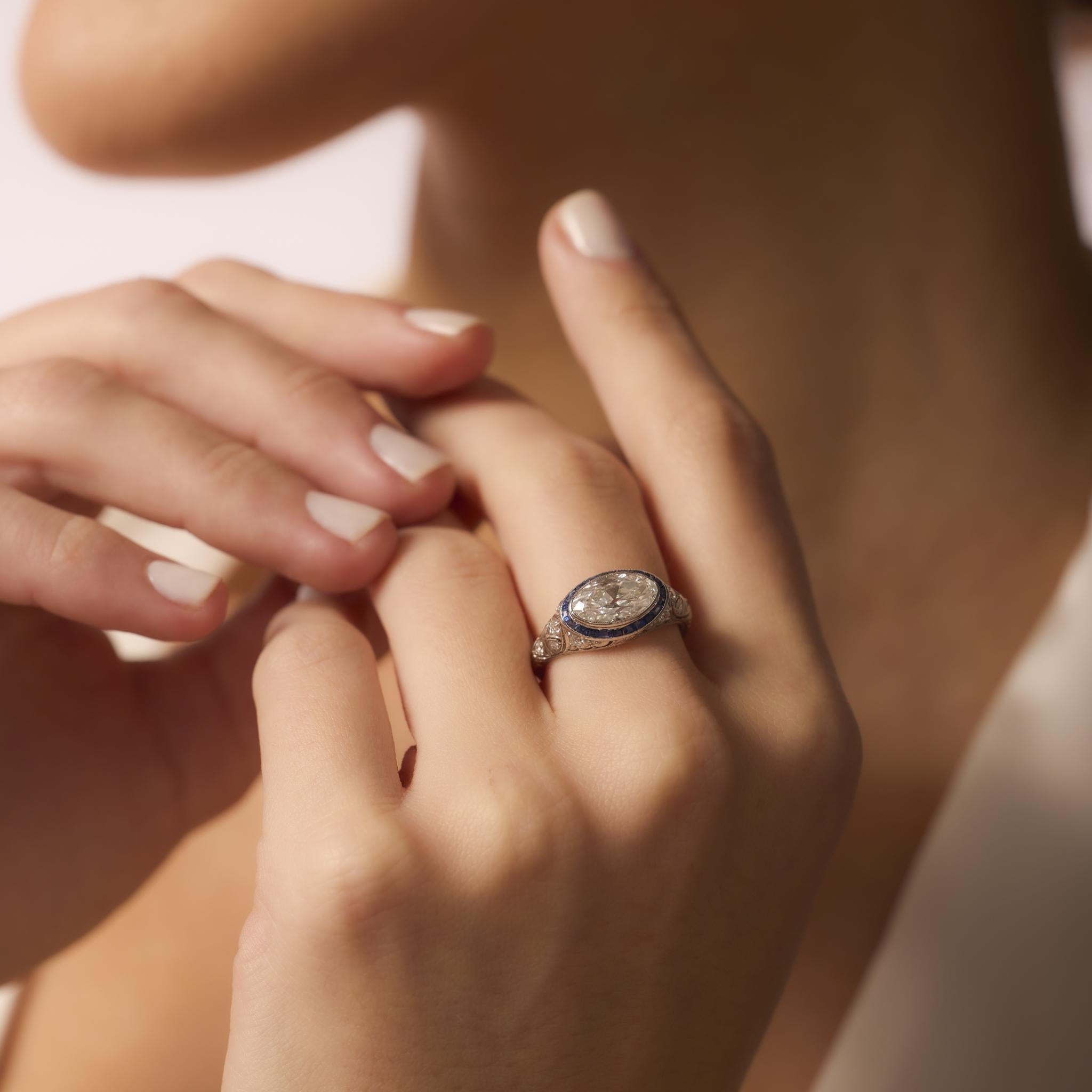 This Art Deco platinum ring showcases a rare 2 carat Moval diamond framed by vivid calibre sapphires and sparkling old European cut diamonds.

This diamond has not been removed from the setting in order to preserve the ring and therefore has not