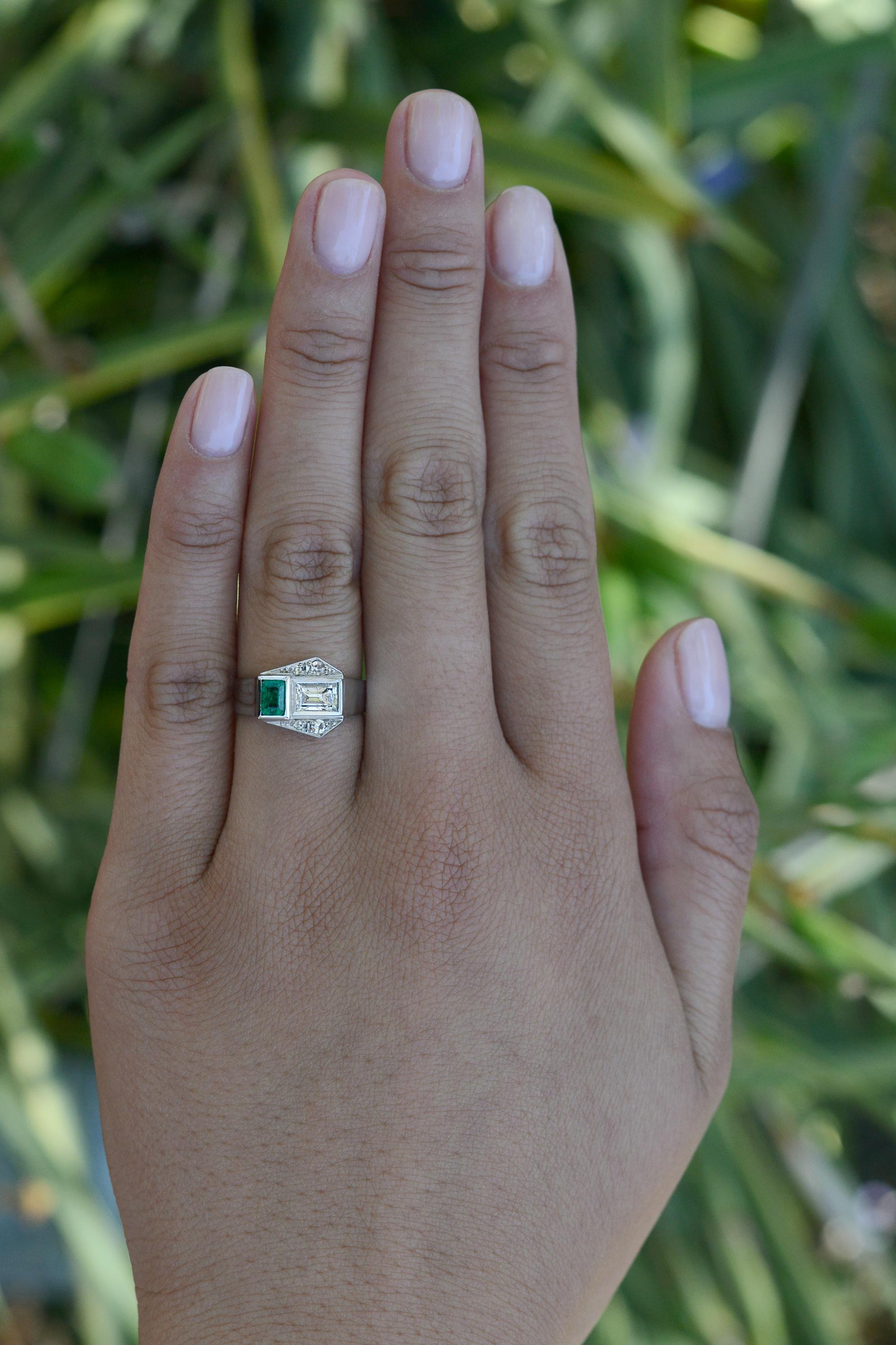 Lovely and unique, this Art Deco 2 stone engagement ring captivates with its rich aesthetic design, showcasing authentic 1920s Art Deco geometry. Featuring an intriguing composition of a sparkling emerald cut diamond and vibrant emerald that