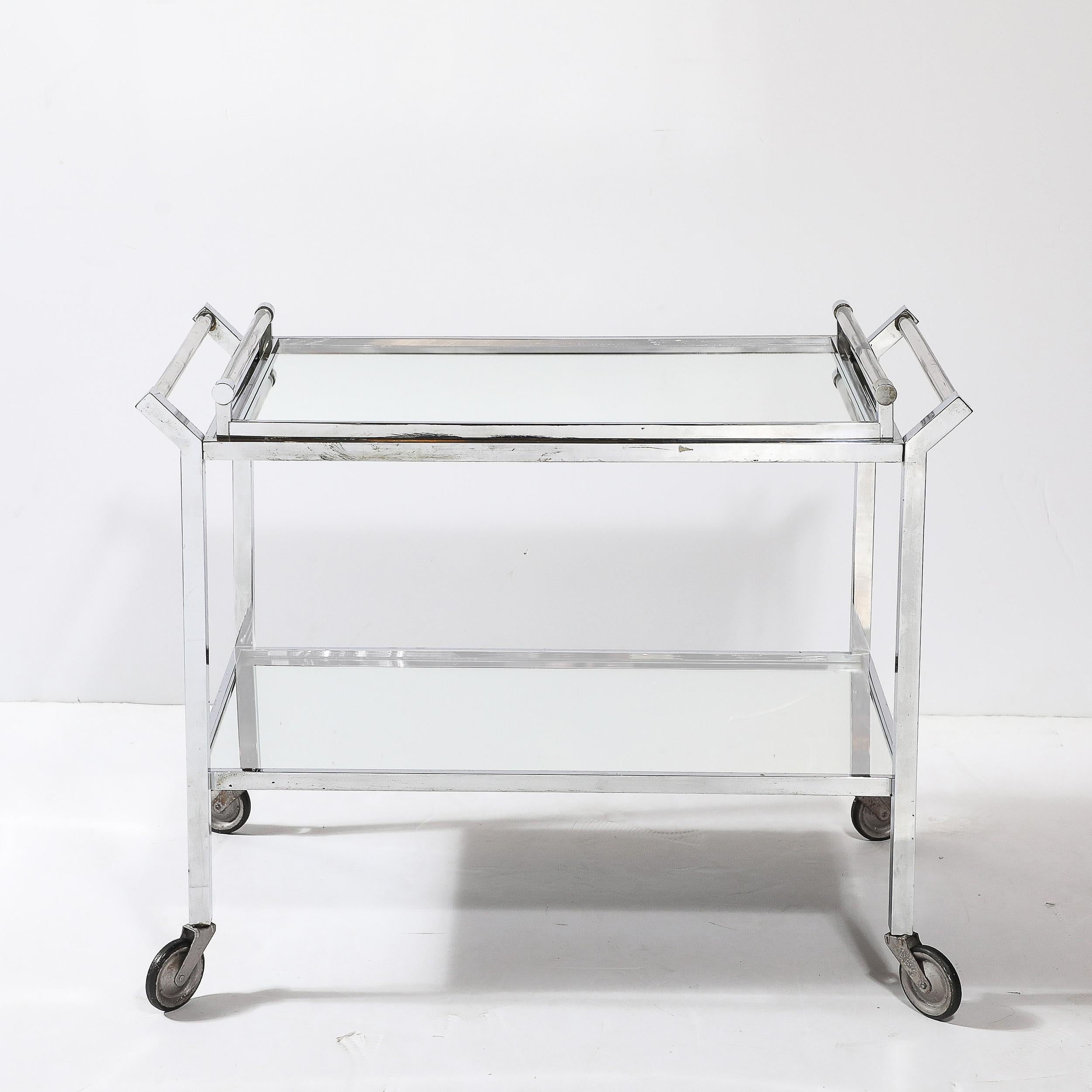 Ce superbe chariot de bar Art déco de Jacques Adnet témoigne du raffinement de l'artisanat et de l'élégance moderne des années 1930. Le chariot présente un design rectiligne symétrique, avec des surfaces en miroir sur les deux niveaux qui amplifient