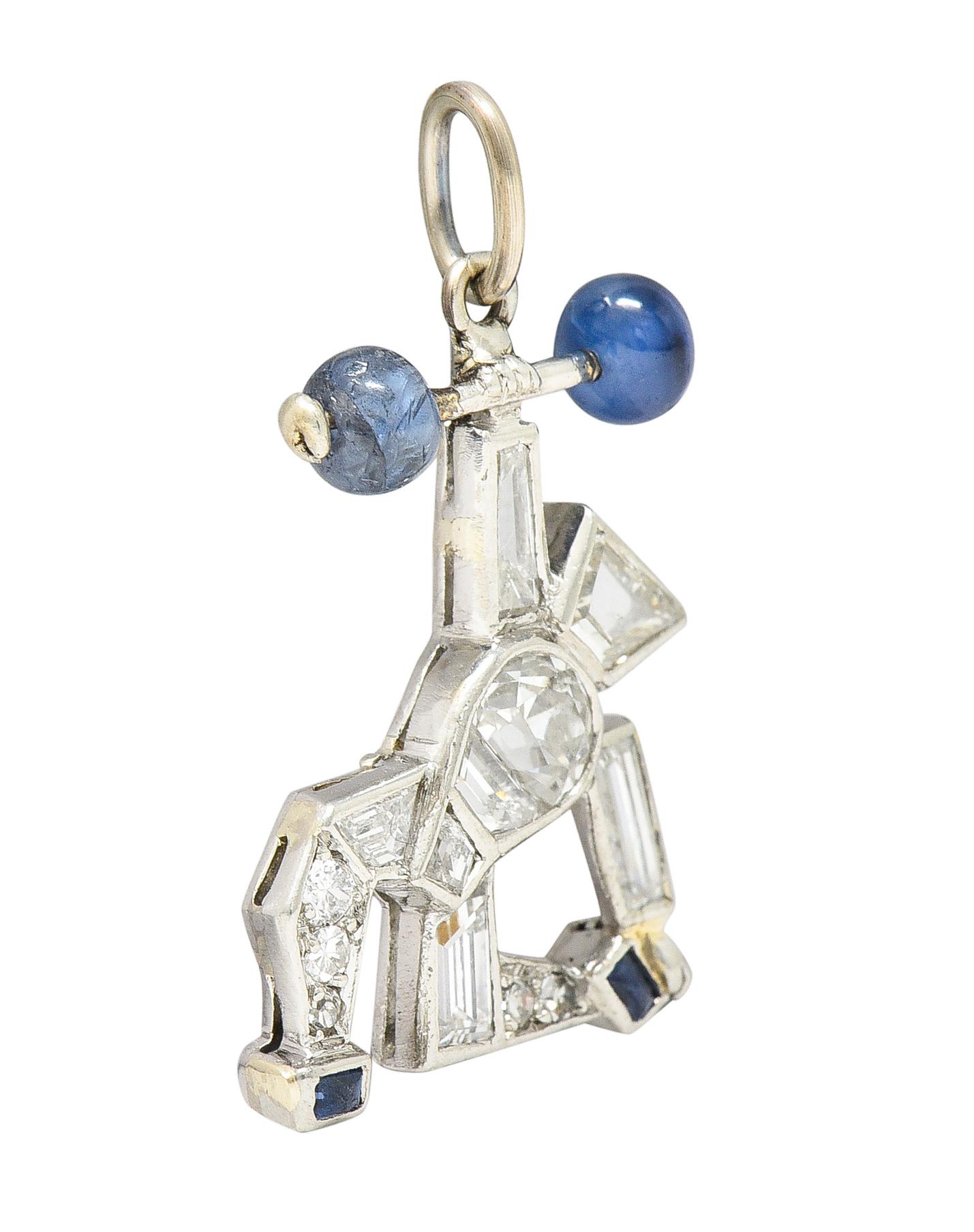 Designed as a geometrically styled strongman motif. Down on one knee and hoisting barbell overhead. Calibré cut sapphire shoes with barbell terminals as riveted sapphire beads. Royal blue in color while weighing collectively approximately 1.00