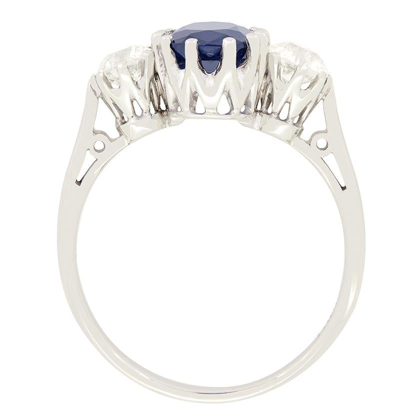 Cette exquise bague trilogie Art déco est ornée d'un magnifique saphir naturel non chauffé en guise de pièce maîtresse. Le saphir de taille coussin pèse un poids impressionnant de 2,00 carats et est solidement serti à l'aide de griffes, ce qui lui