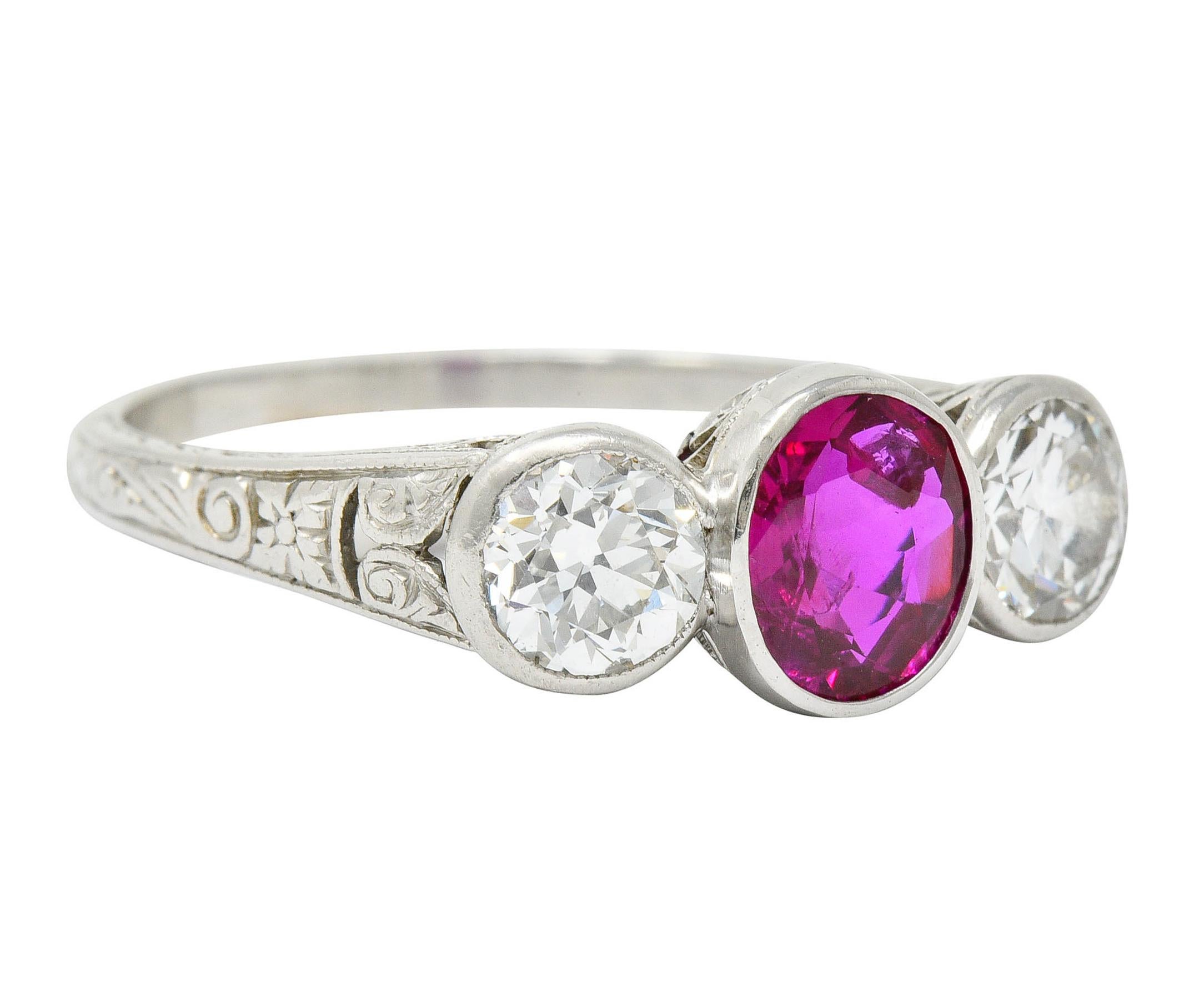 Three stone ring centers a bezel set oval cut Burmese ruby weighing approximately 1.03 carat

Transparent with pinkish-red color and no indications of heat

Flanked by old European cut diamonds weighing in total approximately 1.00 carat; G-H color