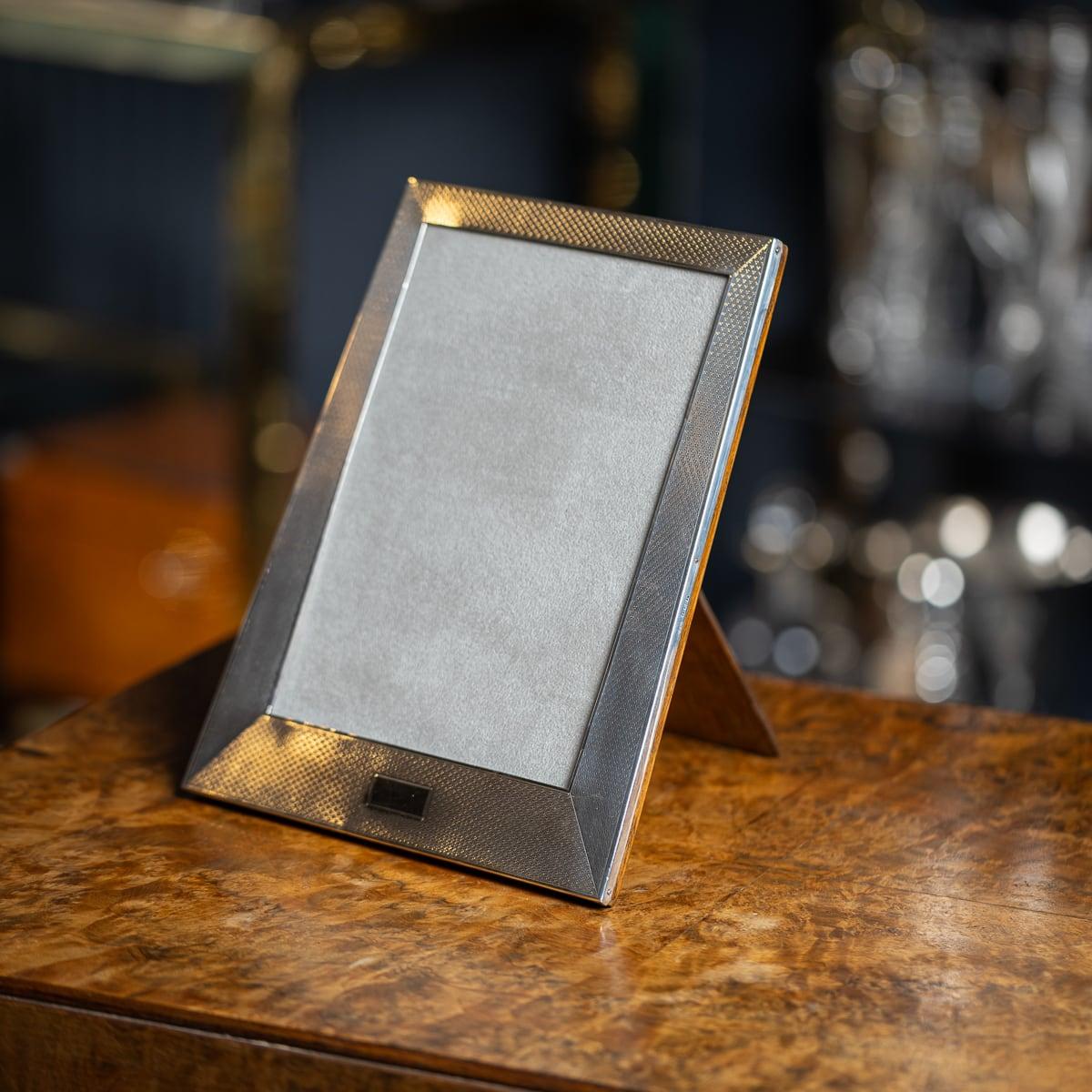 Antique early 20th Century English made solid silver photograph frame, of rectangular form with an engine turned design. The frame features a flared style where the border surrounding the photograph gets wider towards the base. The photo can be