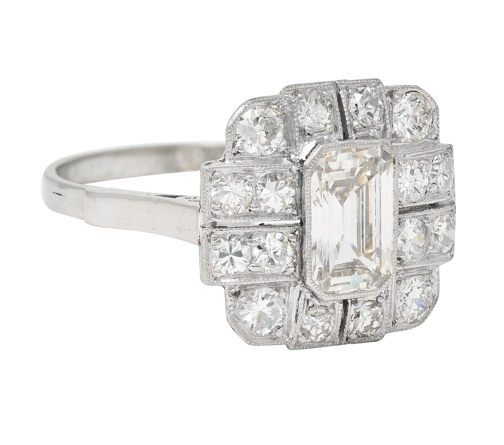 Centering an emerald cut diamond weighing approximately 1.18 carats - M color with VS1 clarity
Set in a milgrain bezel with a pierced geometric surround 
Bead set with old European and single cut diamonds
Weighing approximately 0.92 carats total -