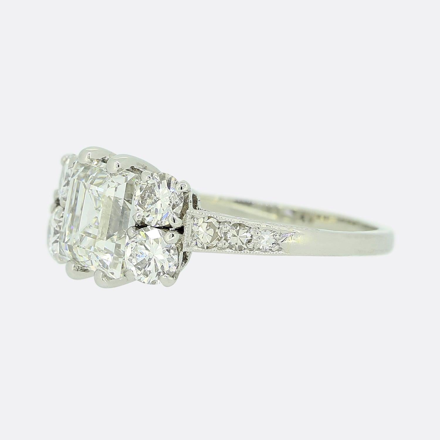Here we have a gorgeous diamond ring crafted at time when the Art Deco style was continuing to revolutionise design. An impressive 2.14ct carre cut diamond sits proud at the centre of the face in a four clawed setting. This principle stone is then