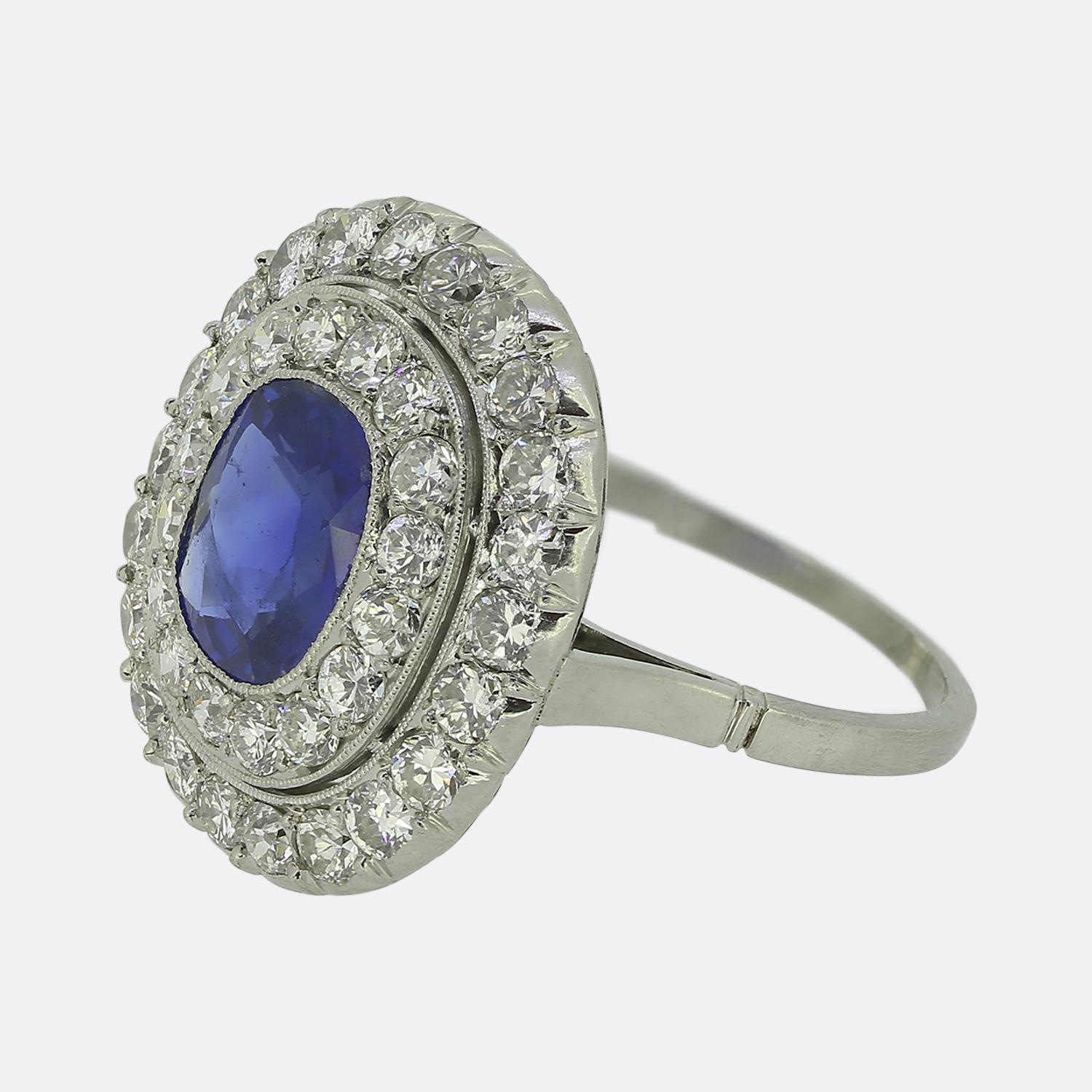 Ecco uno squisito anello a grappolo in platino risalente all'epoca in cui lo stile Art Déco era all'apice del design mondiale. Il suo cuore è costituito da un affascinante zaffiro blu naturale di origine birmana. Questa sensazionale pietra