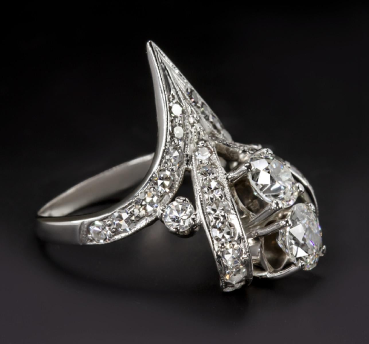 This gorgeous and very high quality vintage diamond cocktail ring has an absolutely one of a kind design featuring two dazzling old European cut diamonds set between curling, diamond encrusted ribbons. The two center diamonds are quite substantial
