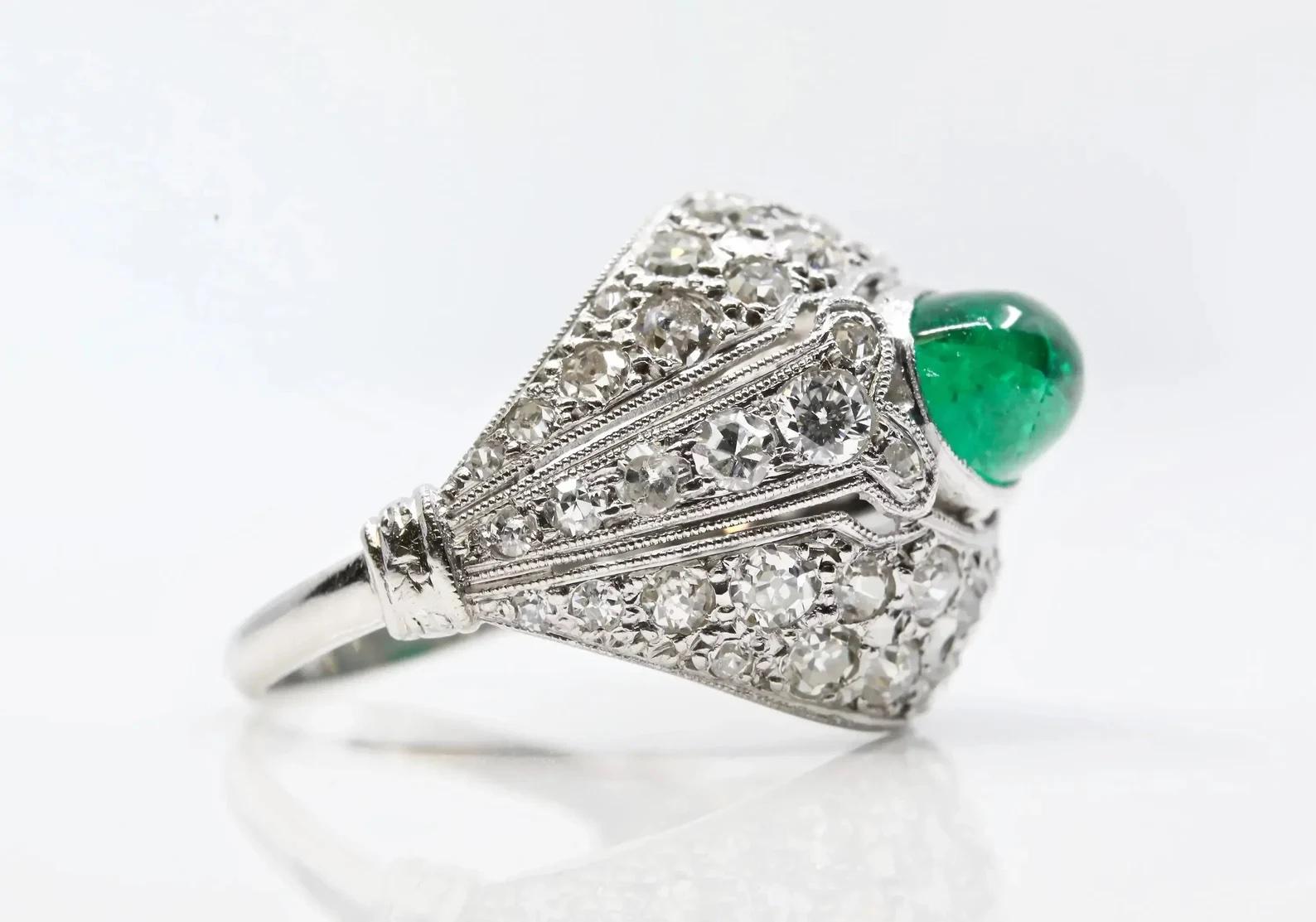 A handmade French Art Deco period Cabochon Emerald, and diamond ring in platinum. Weighing approximately 2.20 carats, the center bezel set emerald is a beautiful Colombian gem of gorgeous rich vivid green color. Accenting the emerald are a total of