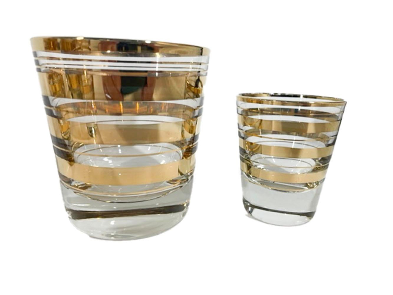 Set of 12 Art Deco cocktail glasses - 6 old fashioned glasses and 6 shot glasses all with wide 22 karat gold bands between pairs of narrow gold lines, all on clear glass.