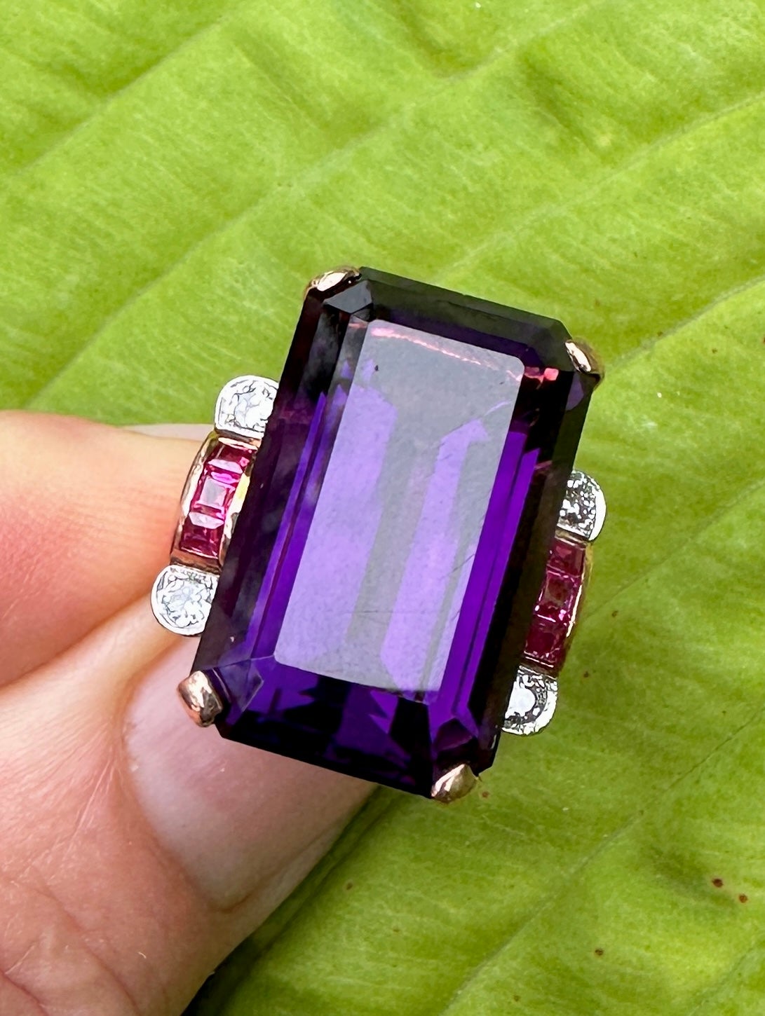 THIS IS A MAGNIFICENT ANTIQUE ART DECO - RETRO 23 CARAT EMERALD CUT SIBERIAN AMETHYST RING WITH FOUR GORGEOUS OLD MINE CUT DIAMONDS AND SIX SPECTACULAR SQUARE CHANNEL SET RUBIES IN 14 KARAT ROSE GOLD.  THE STUNNING MONUMENTAL 23 CARAT SIBERIAN