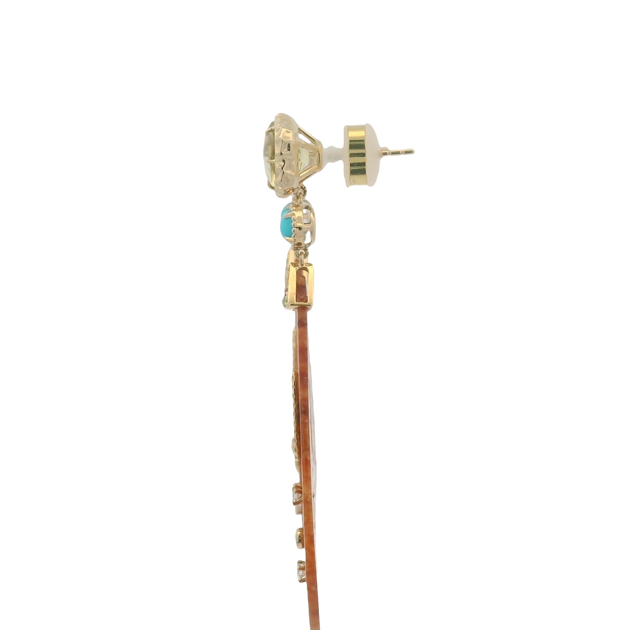 These extraordinary earrings are crafted in 14 karat yellow gold and bring together a captivating medley of gemstones and textures. The centerpiece features hand-carved jade drops (23.37 ct) in a warm cinnamon-orange hue, delicately pierced with