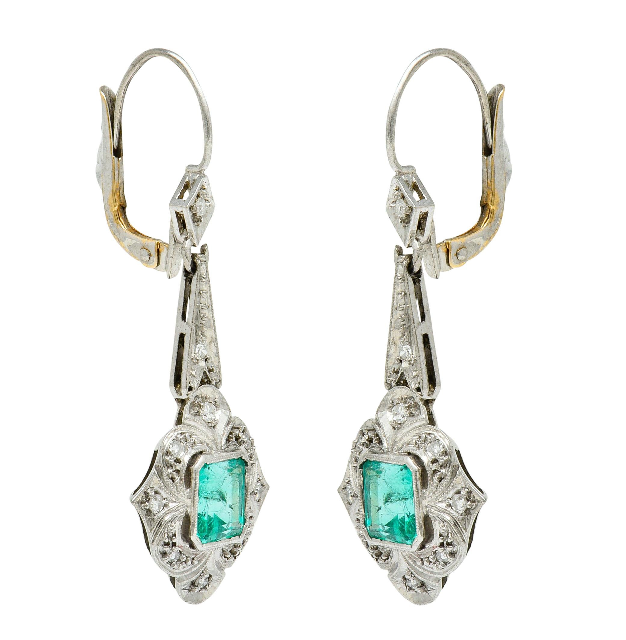 Drop earrings are designed as stylized quatrefoils with milgrain edges

Centering emerald cut emeralds weighing in total approximately 2.00 carats

Very well-matched, transparent, and vibrantly bluish-green in color; one has a surface reaching