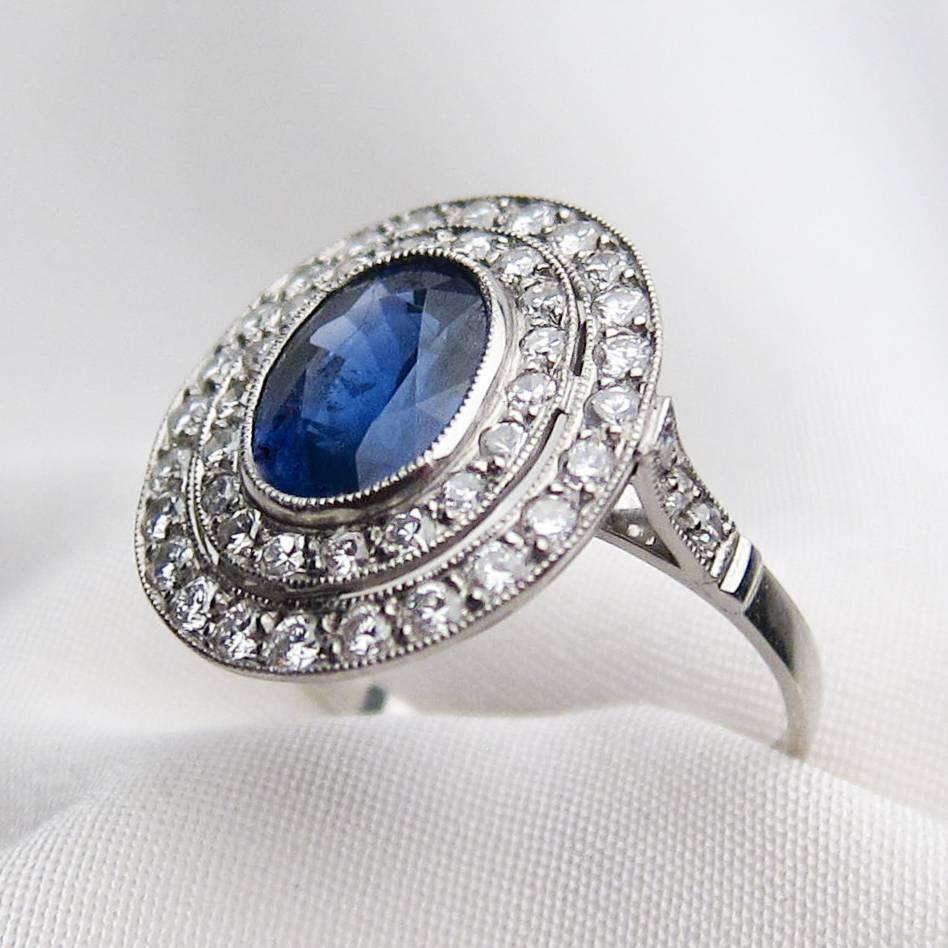 Circa 1930. This beautiful Art Deco halo ring features a lovely central oval mixed-cut natural deep blue sapphire weighing 2.36 carats. Surrounding the sapphire in a double halo are 42 round single-cut diamonds set in platinum. Three diamonds accent