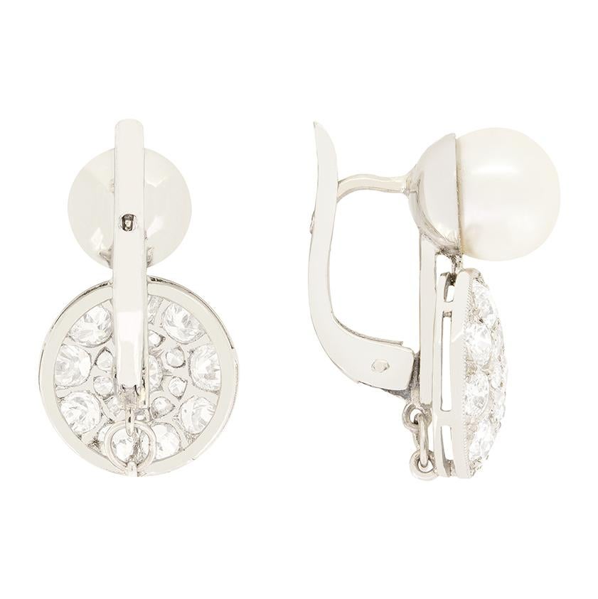 Crafted in the Art Deco period, these enchanting earrings feature beautiful pearls with diamonds gracefully dropping below. Each pearl is 8mm in size and set into platinum. The sparkling drops both feature a central 0.10 carat old cut diamond, with