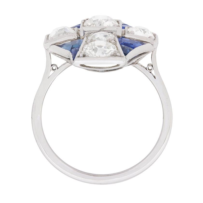 Three old cut diamonds, each grain set within a box collet, comprise the horizontal centre of this unmistakably Art Deco cocktail ring. A graduating pair of grain set, old cut diamonds flanks the centre diamond vertically, forming a cross design,
