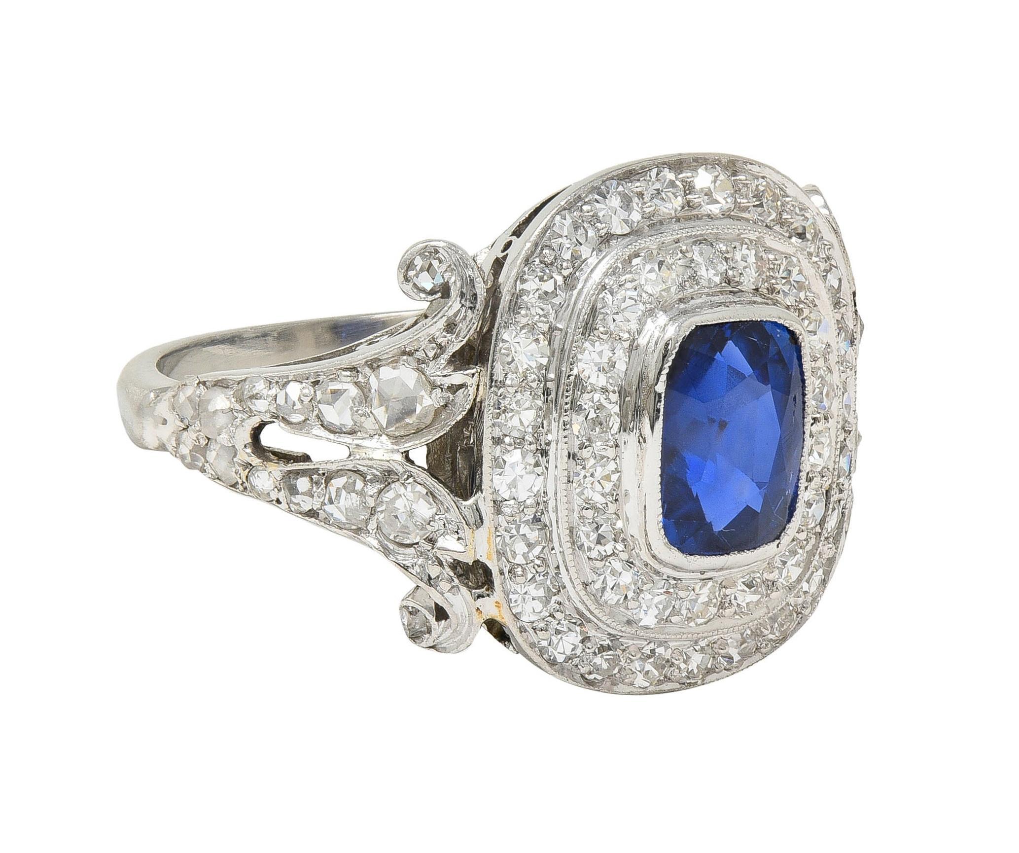 Centering a cushion cut sapphire weighing 1.30 carats - transparent medium blue in color
Natural Burmese in origin and displaying no indications of heat treatment 
Bezel set with a tiered double halo surround of single cut diamonds 
With additional
