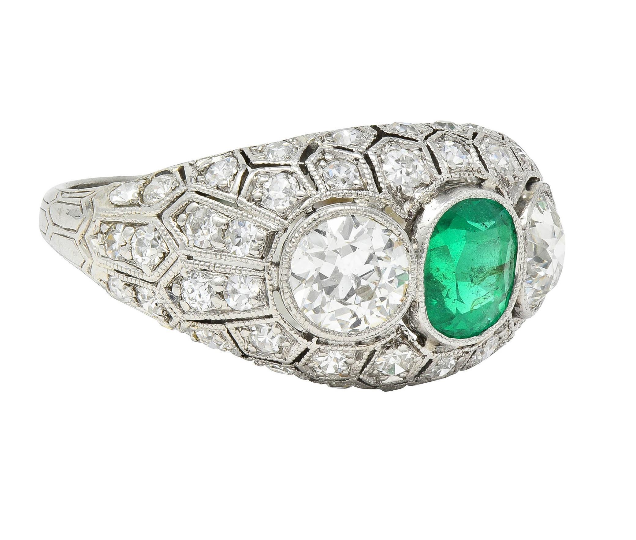Centering a cushion cut emerald weighing approximately 0.85 carat 
Transparent medium green in color and set in milgrain bezel 
Flanked by old European cut diamonds set in matching bezels
Weighing approximately 1.00 carats total - J color with SI1
