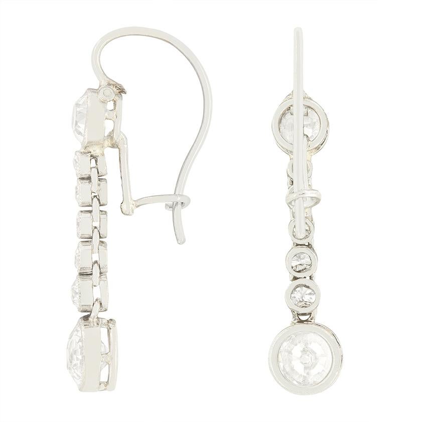 These delightful Art Deco drop earrings feature a graceful cascade of seven old cut diamonds on each earring, totalling 0.40 carats. The largest of these diamonds sit at the top and bottom, weighing 0.40 carat and 0.60 carat respectively. Each of