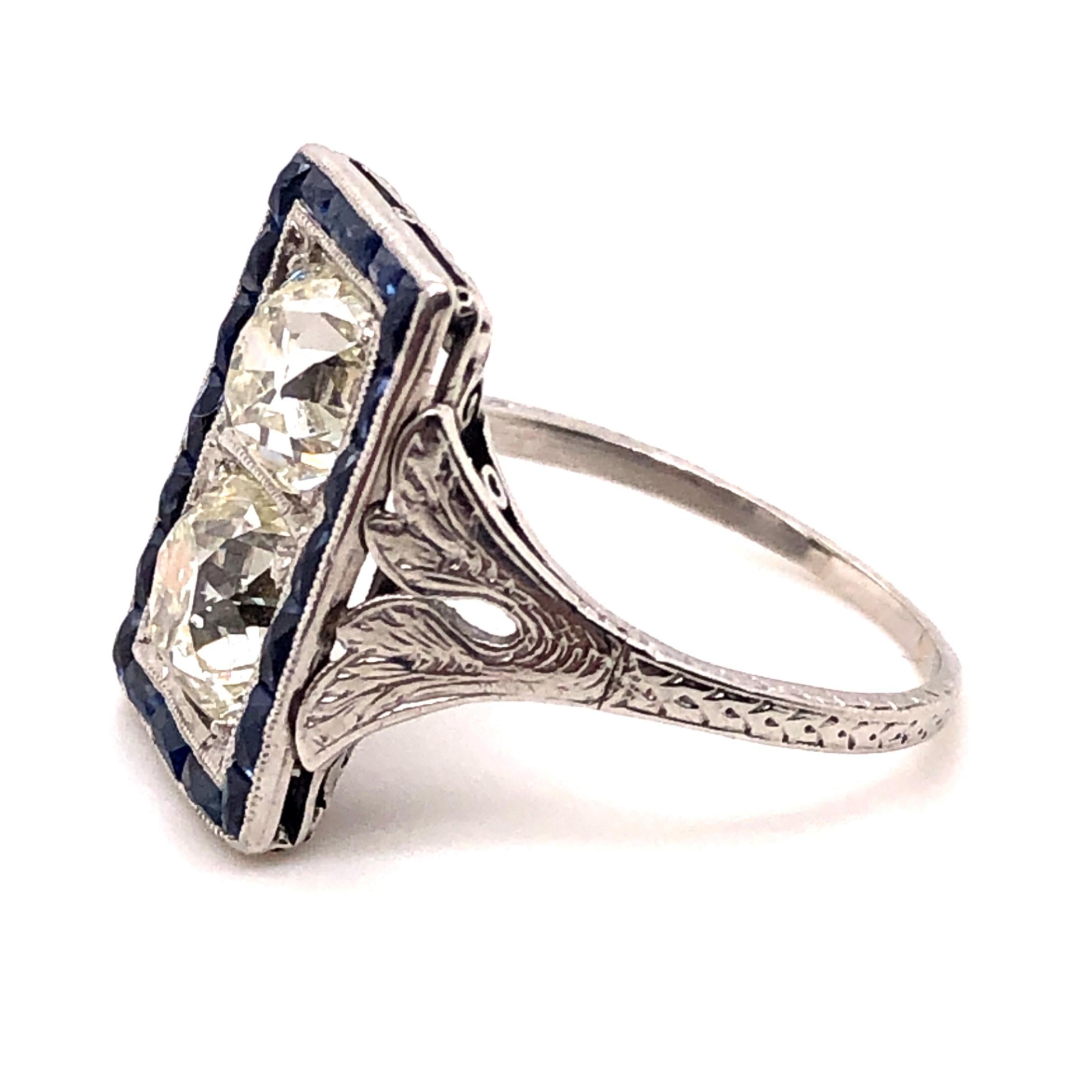Art Deco Platinum 2.58 total carat weight Old Mine Cut diamond ring. The Old Mine Cut diamonds are set Toi Et Moi style and grade as M color SI1 clarity by GIA  Graduate Gemologists. Surrounding the two center diamonds are French Cut sapphires