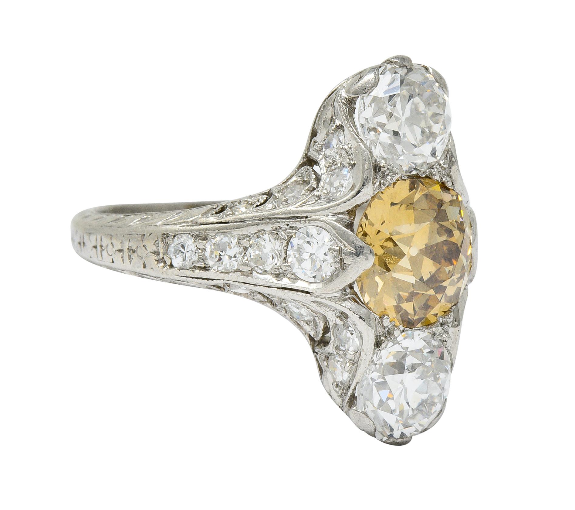 Dinner style ring features ornate scrolling with deeply engraved foliate and orange blossoms partially down shank

Centering a fancy orangey-brown old European cut diamond weighing approximately 1.07 carats with VS1 clarity

Flanked North and South