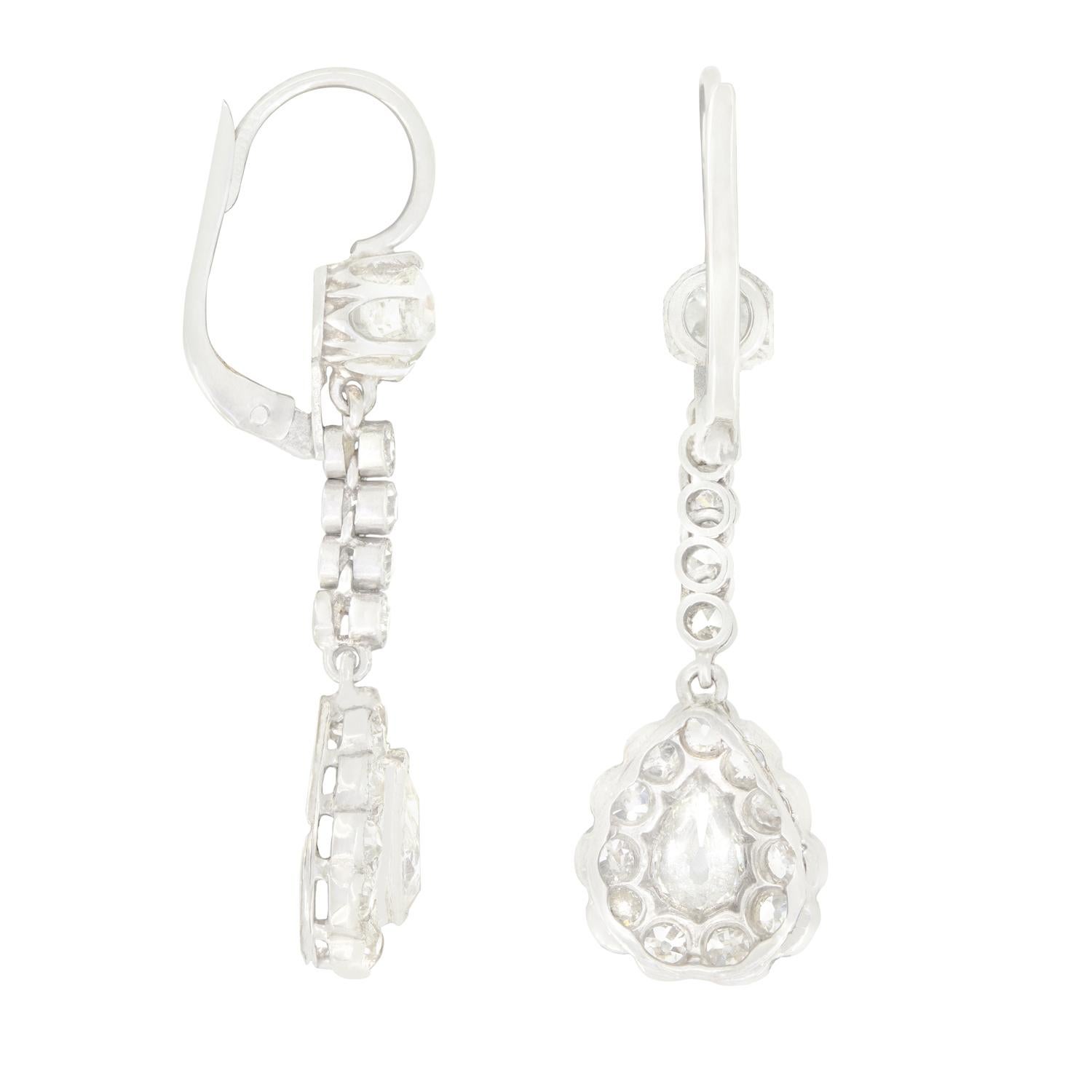Fechados en la década de 1920, estos preciosos pendientes art déco presentan una brillante gota de diamantes. Cada gota de los pendientes centra un diamante talla pera antigua de 0,40 quilates, rodeado por 0,55 quilates de diamantes talla antigua en