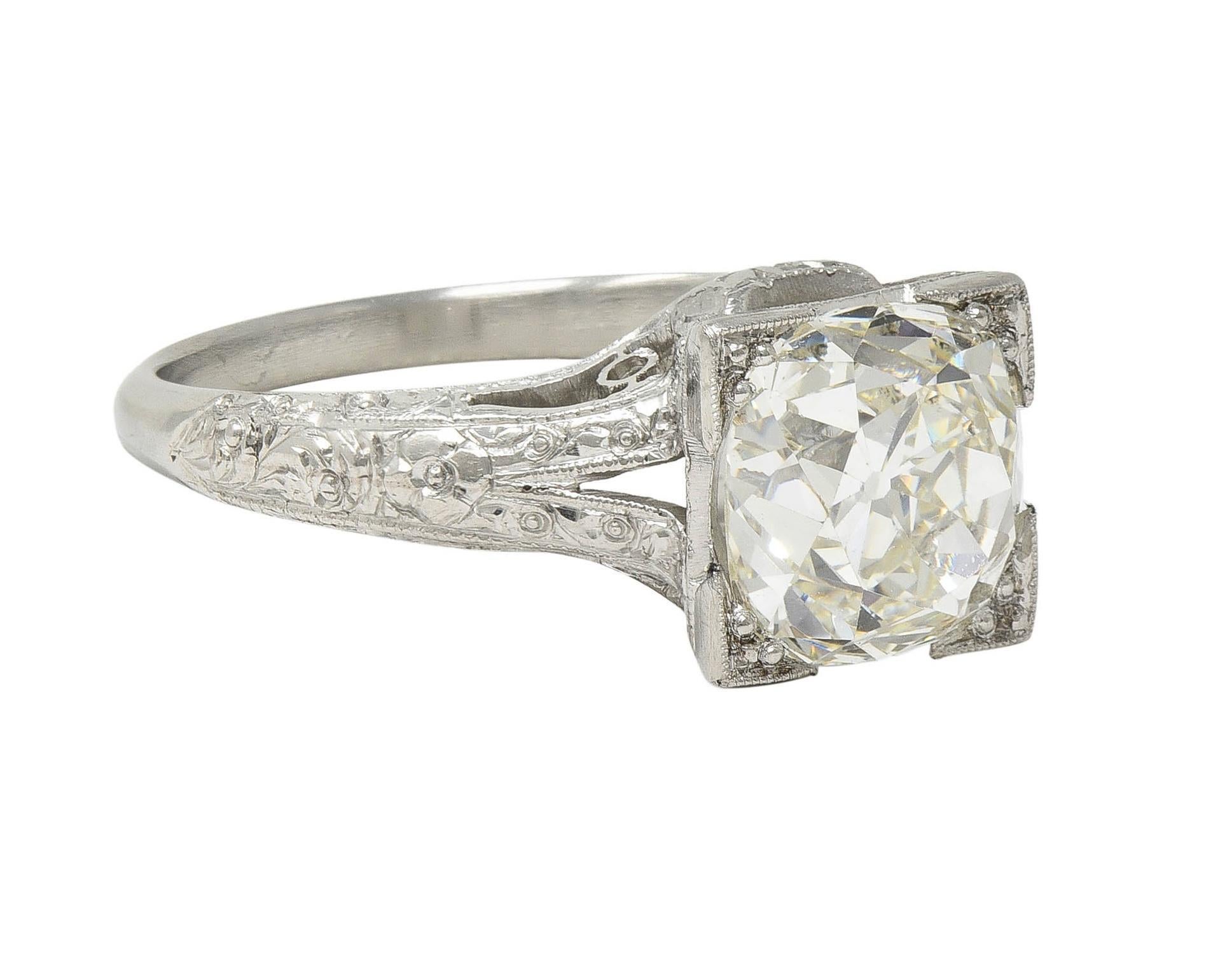 Centering an old mine cut diamond weighing 2.65 carat total - K color with VS1 clarity
Bead set in a square form head with milgrain edges and flanked by cathedral shoulders
Pierced with engraved orange blossom and scrolled motif details
Stamped for