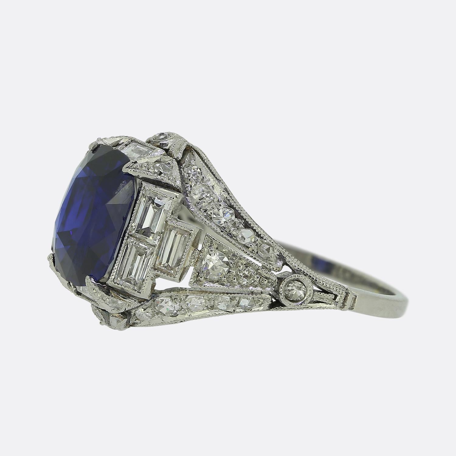 Cette exquise bague Art déco est réalisée en platine. En son cœur se trouve un saphir bleu captivant de 2,70 carats, qui attire l'attention par sa teinte profonde. Autour de cette pierre principale, des diamants droits de taille baguette sont