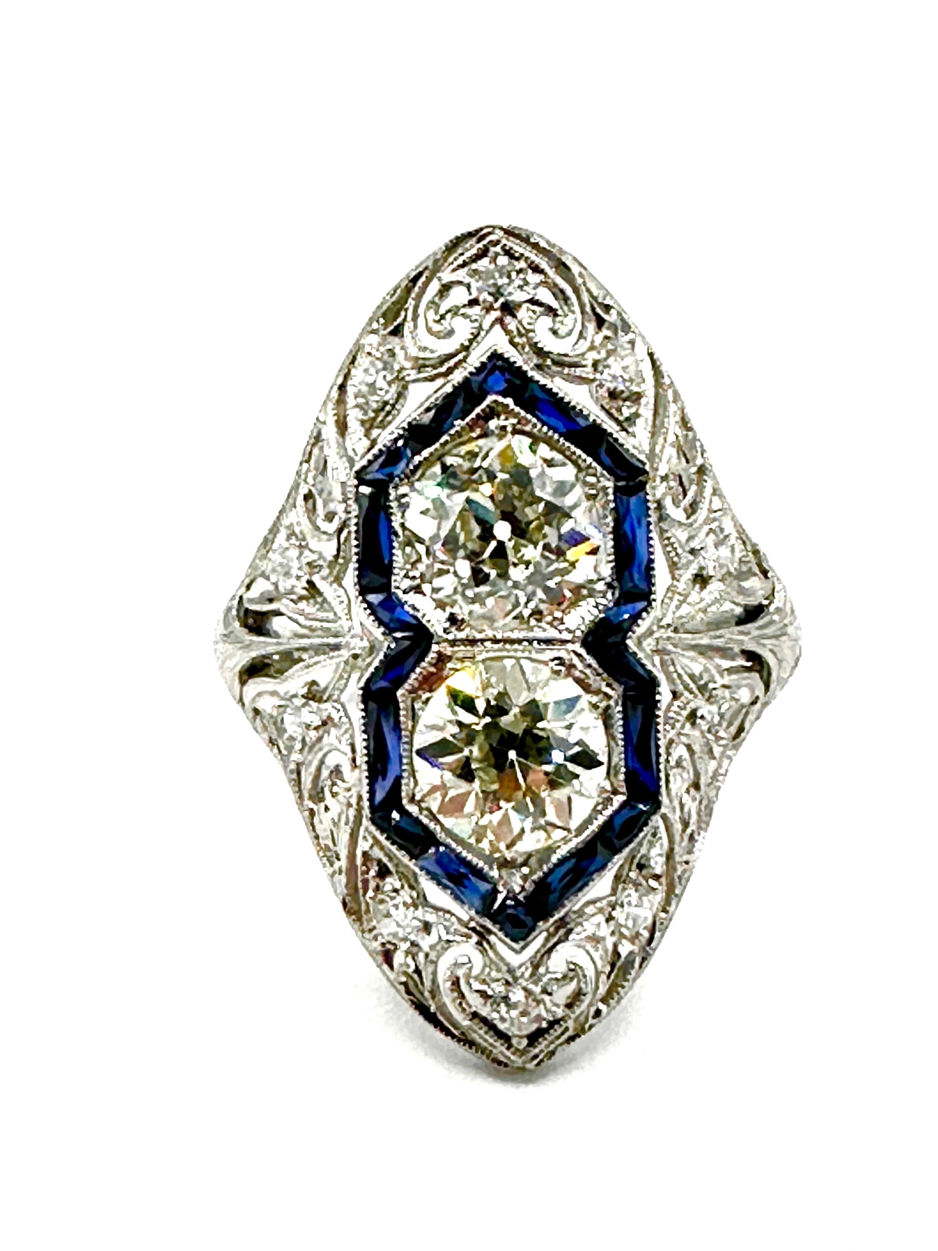 A mind blowing stunner of an Art Deco ring!  This ring features two large old European cut Diamonds in the center, surrounded by a single row frame of French cut Sapphires, and open platinum metal work with single cut Diamonds.  The center Diamonds