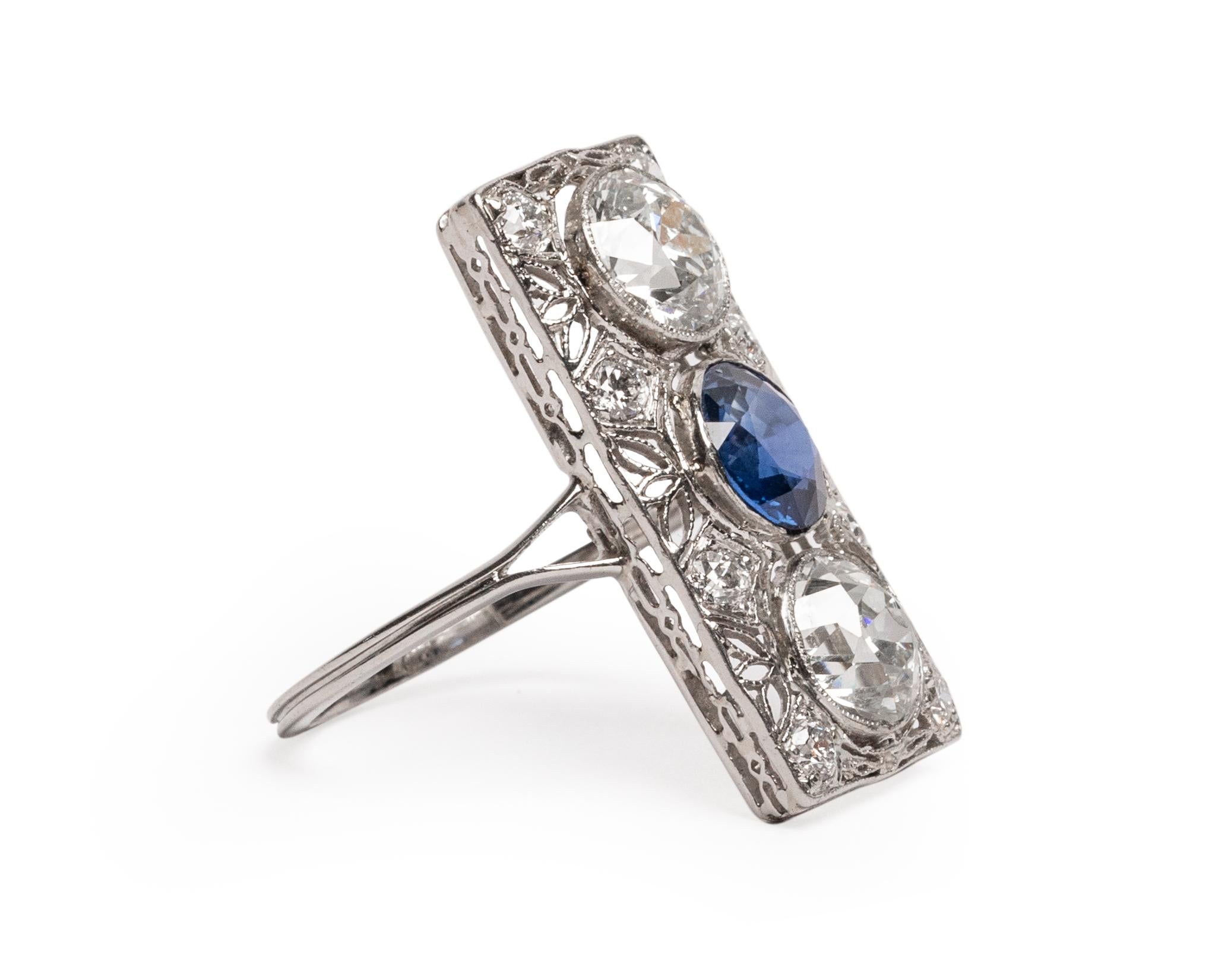 Here we have a stunning example of an Art Deco era cocktail ring! The stunning elongated rectangle is topped with two old european cut fireballs and a deep royal blue sapphire. Each of these stunning gems are bezel set and surrounded by intricate