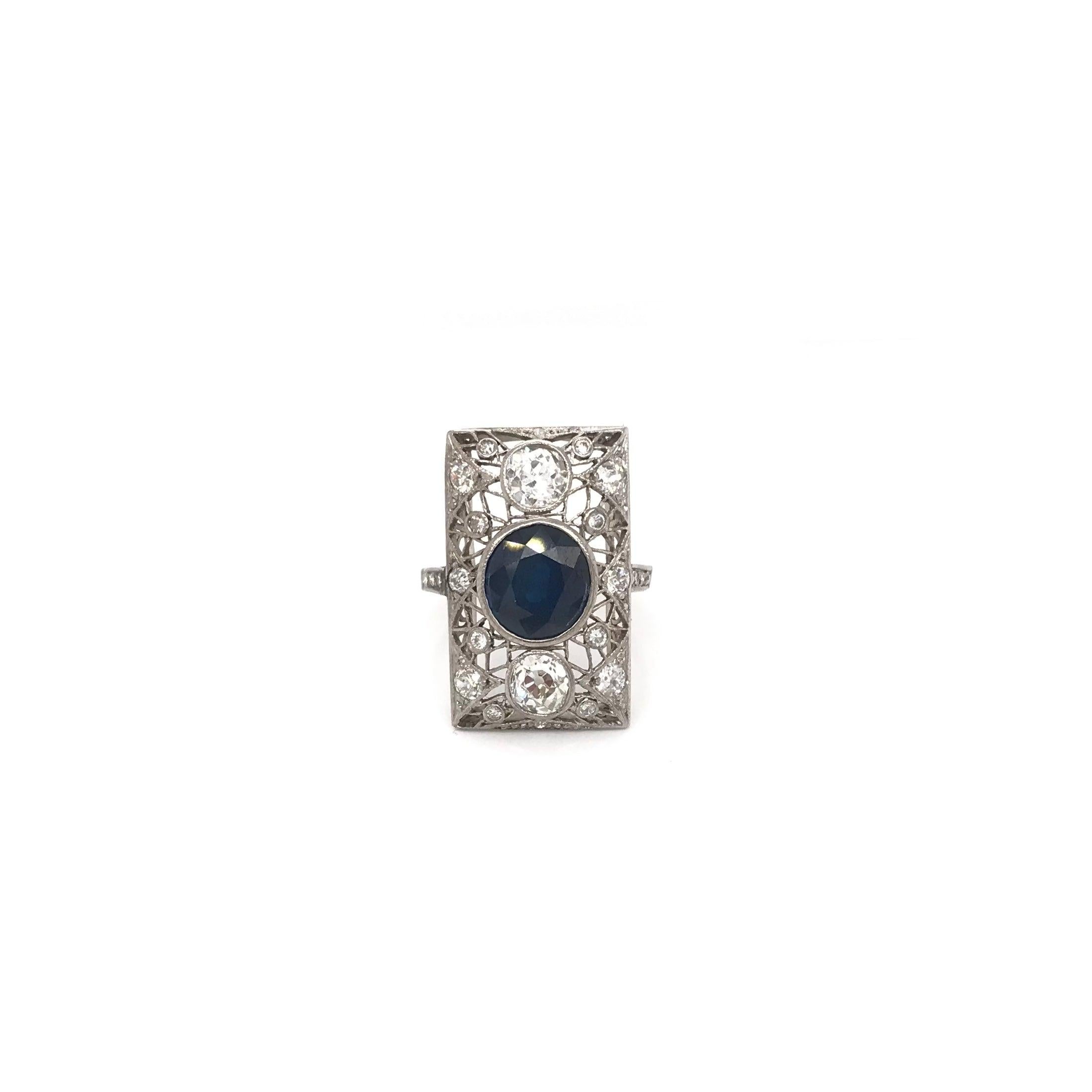 This antique piece was handcrafted sometime during the Art Deco design period (1920-1940). The center stone is a gorgeously rich blue sapphire. The central blue sapphire measures approximately 3 full carats. The platinum setting features one diamond