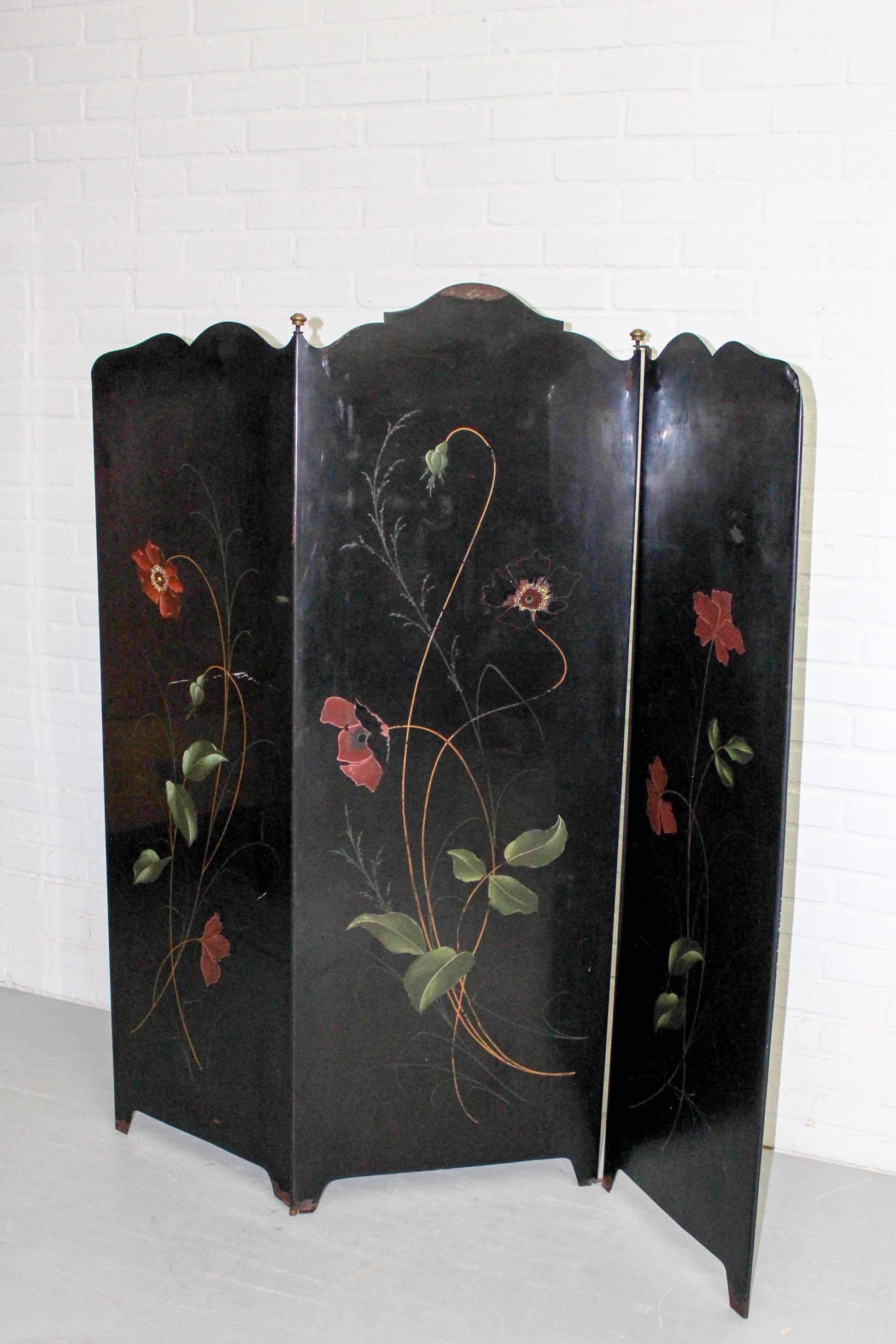 Fabulous Art Deco three-panel folding screen or room divider comprised of black metal with painted flowers and brass knobs. Lovely vintage condition, with some damage but no restorations. Dimensions: 135cm H, 130cm W.