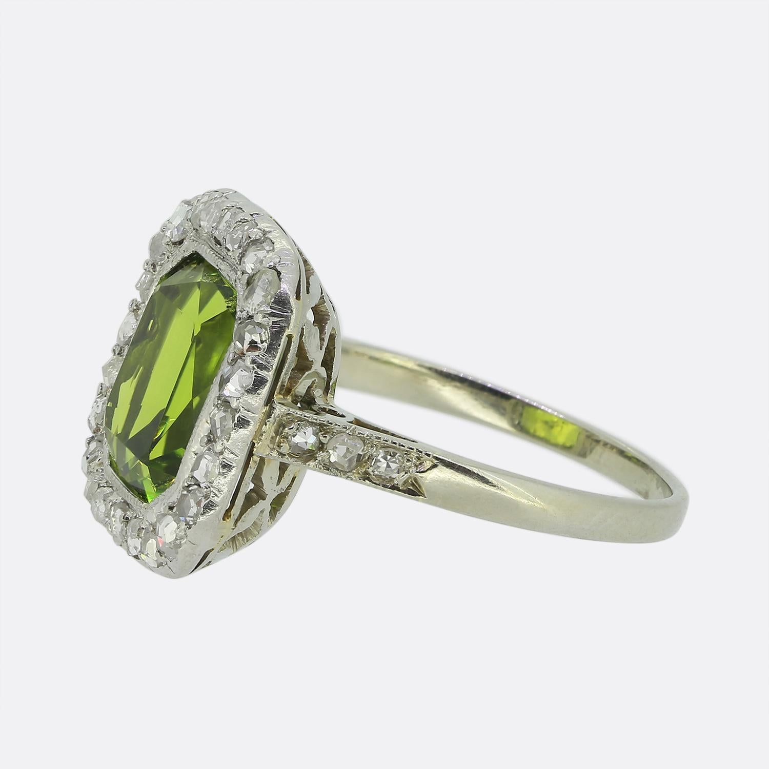 Aquí tenemos un llamativo anillo en racimo con un vibrante peridoto verde en el centro, tallado con maestría para captar la luz. Rodeando esta radiante piedra principal hay un marco de brillantes diamantes talla rosa alrededor del borde exterior;