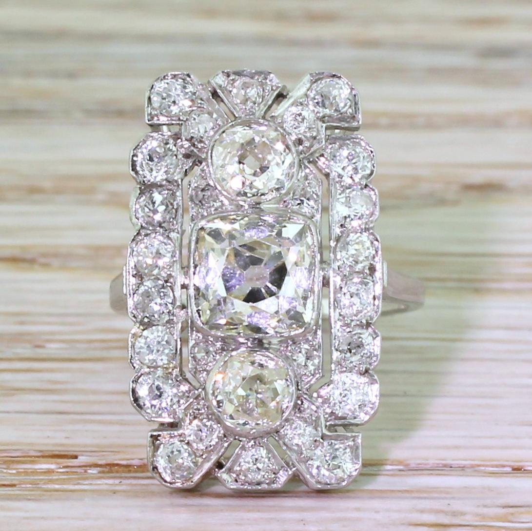 The centrepiece of this majestic ring is a 1.50 carat square / cushion shaped old cut diamond, which is flanked either side by a pair of round old cut diamonds. The beautifully pierced and detailed gallery features a further twenty six old cut