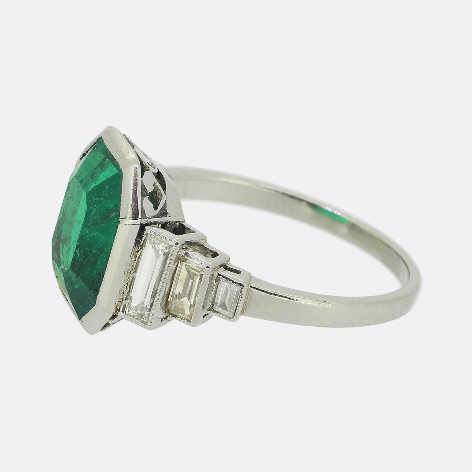 Here we have an exquisite Art Deco ring. This elegant piece has been crafted from platinum and showcases a captivating emerald-cut Colombian emerald at the centre. The vibrant green hue of the emerald is beautifully complemented by baguette-cut