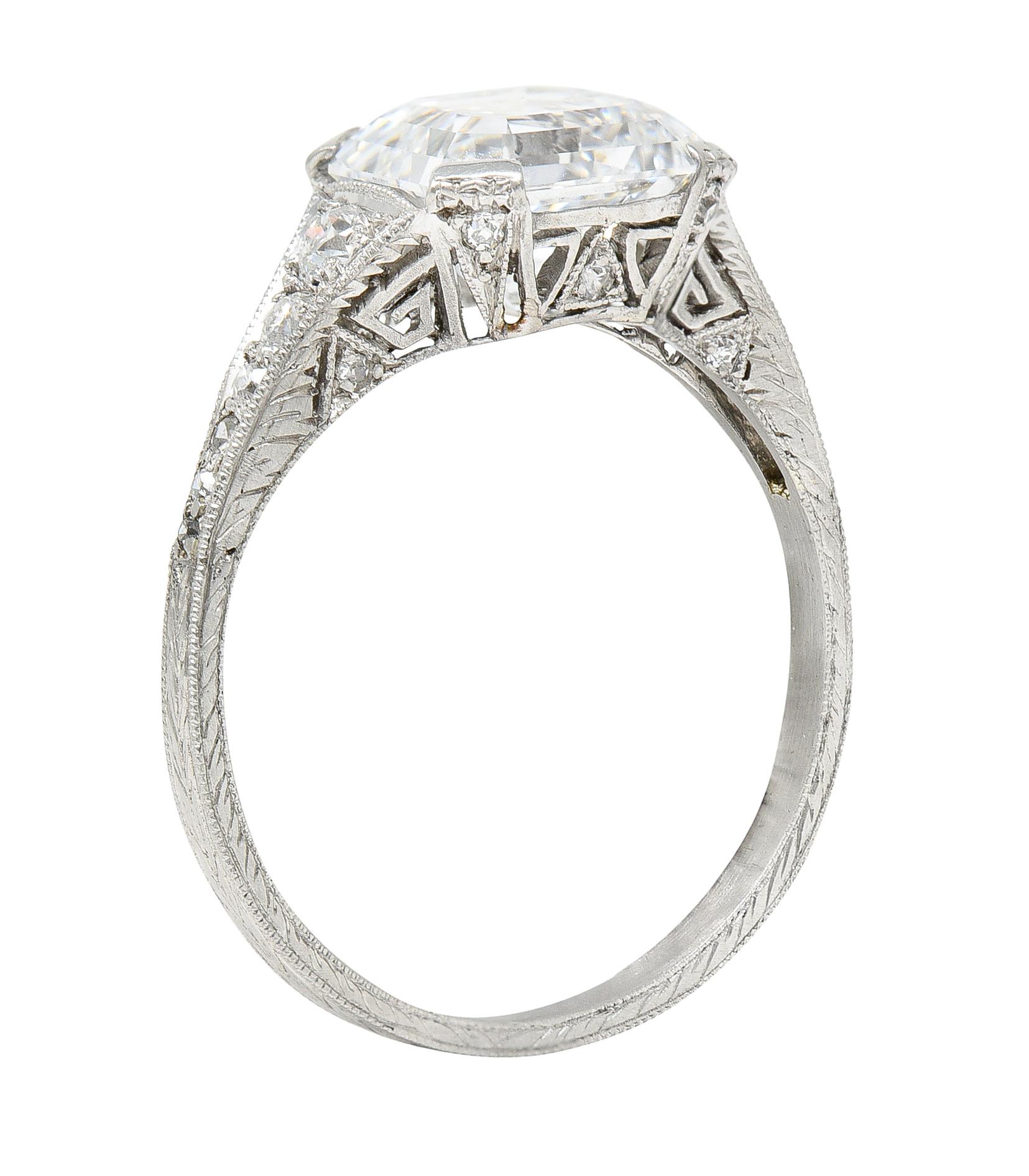 Featuring an asscher cut diamond weighing 2.87 carats - E color with VS2 clarity

Set East to West by wide prongs with a pierced stylized gallery

Depicting a triangle motif flanked by Greek Keys and engraved foliate fully around shank

Accented by