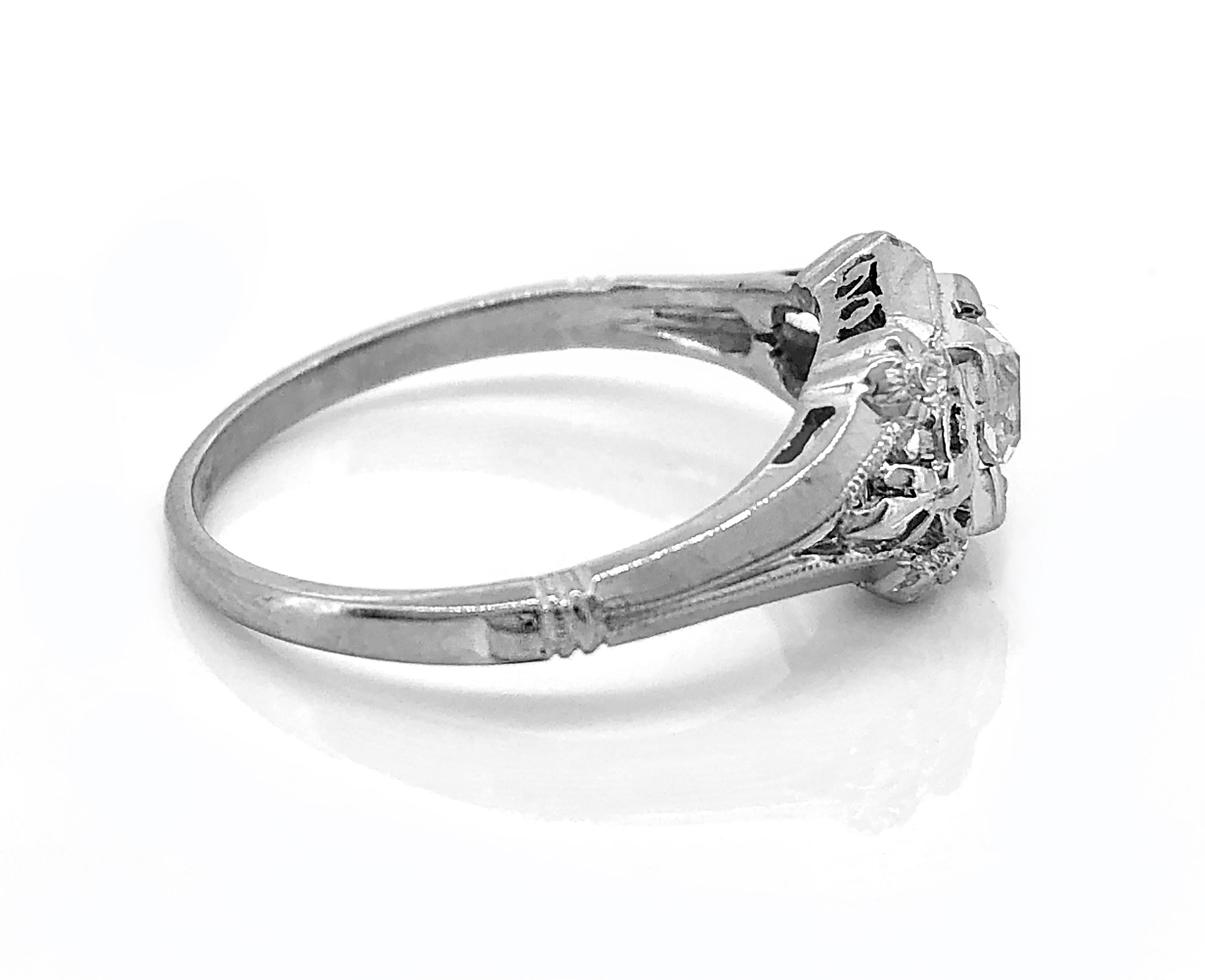 A darling 18k White Gold Art Deco diamond Antique engagement ring that features a .33ct. apx. European cut diamond with SI1 clarity and G color. There are 4 flowers on the edge of the head of the ring and it is beautifully pierced and milgrained.